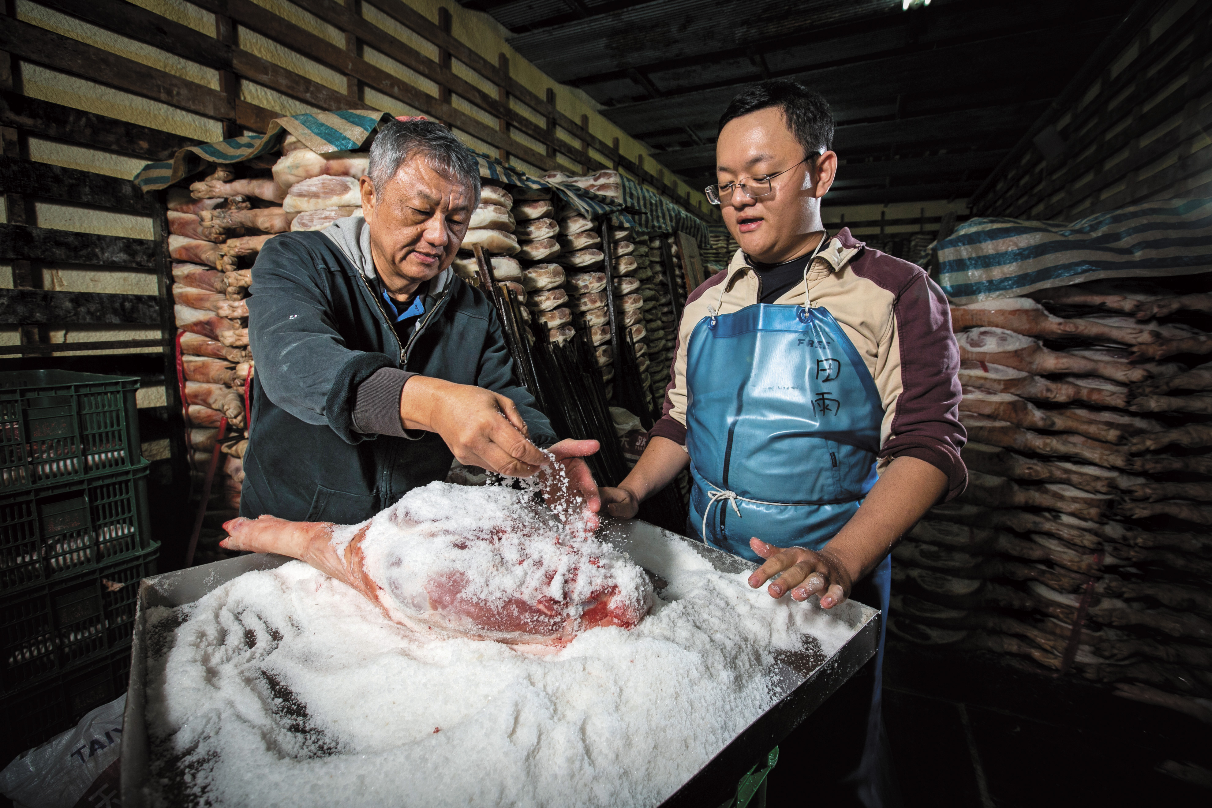 田種苗（左）的小兒子田雨（右）5年前回家接手工廠事務，笑稱鹽漬火腿的步驟，把指紋都磨平了。