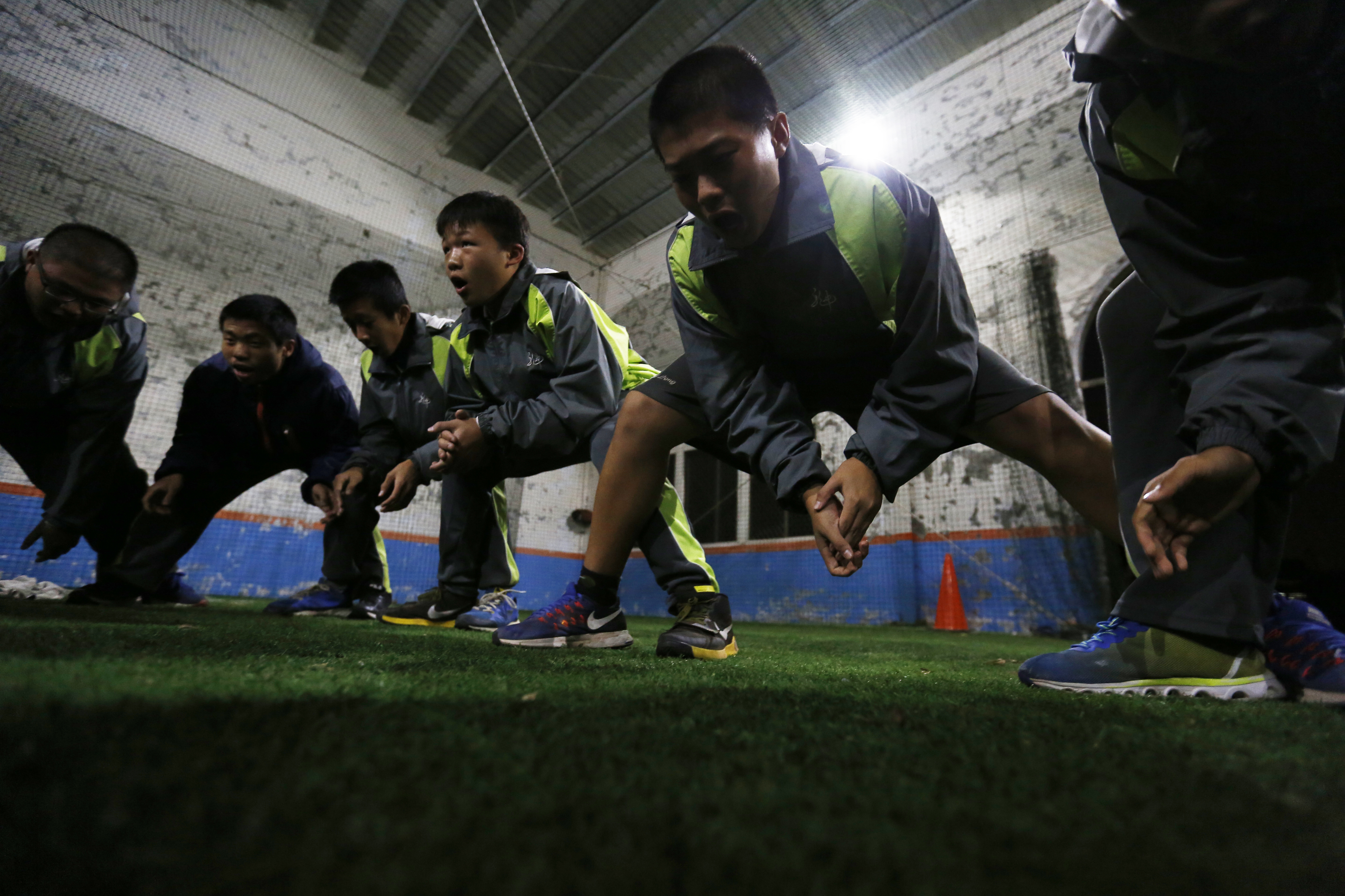 後龍國中棒球隊學生在體育場內蹲低練習。