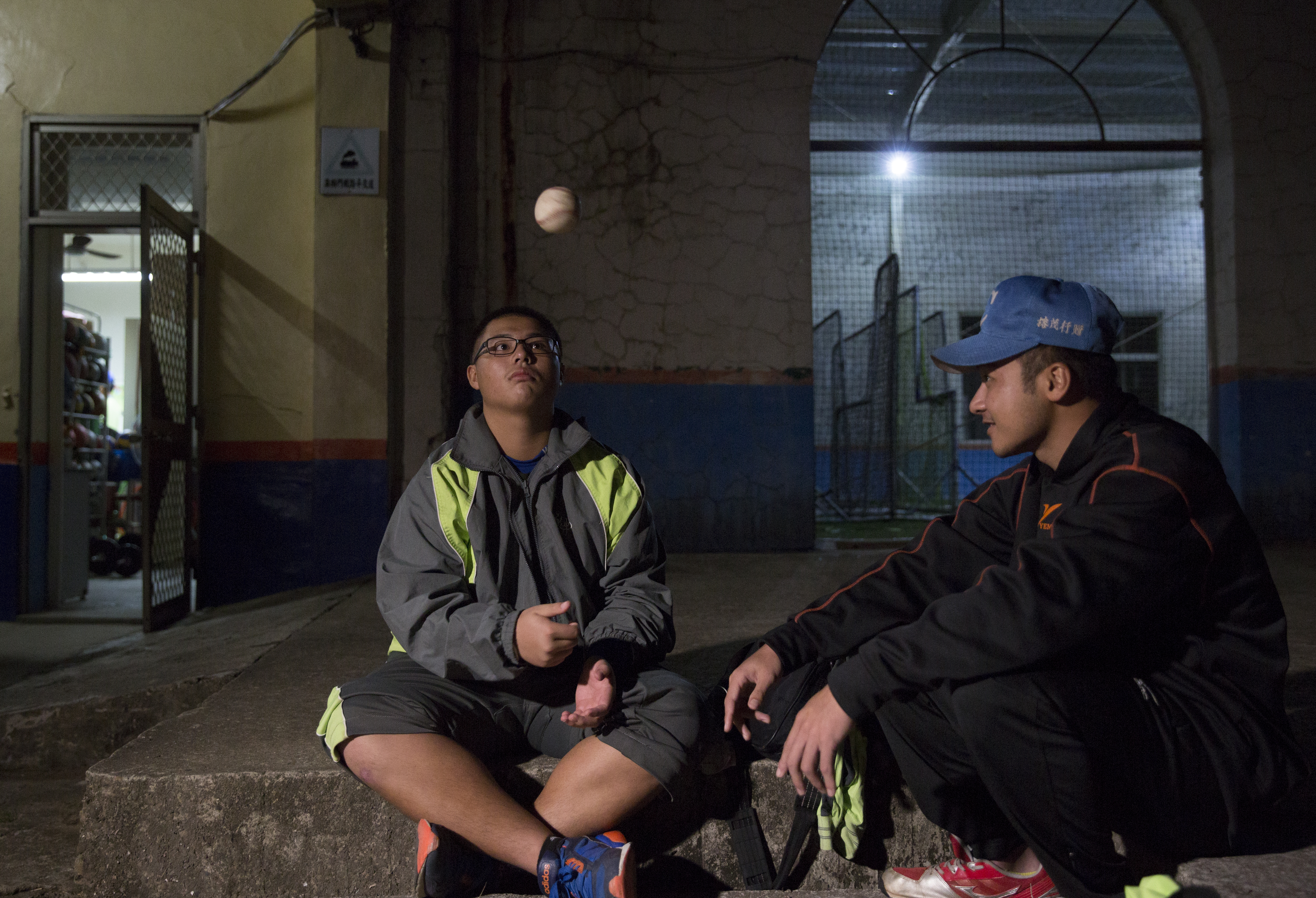 球隊練習結束後，學生和助理教練(右)一邊把玩著棒球一邊閒聊。
