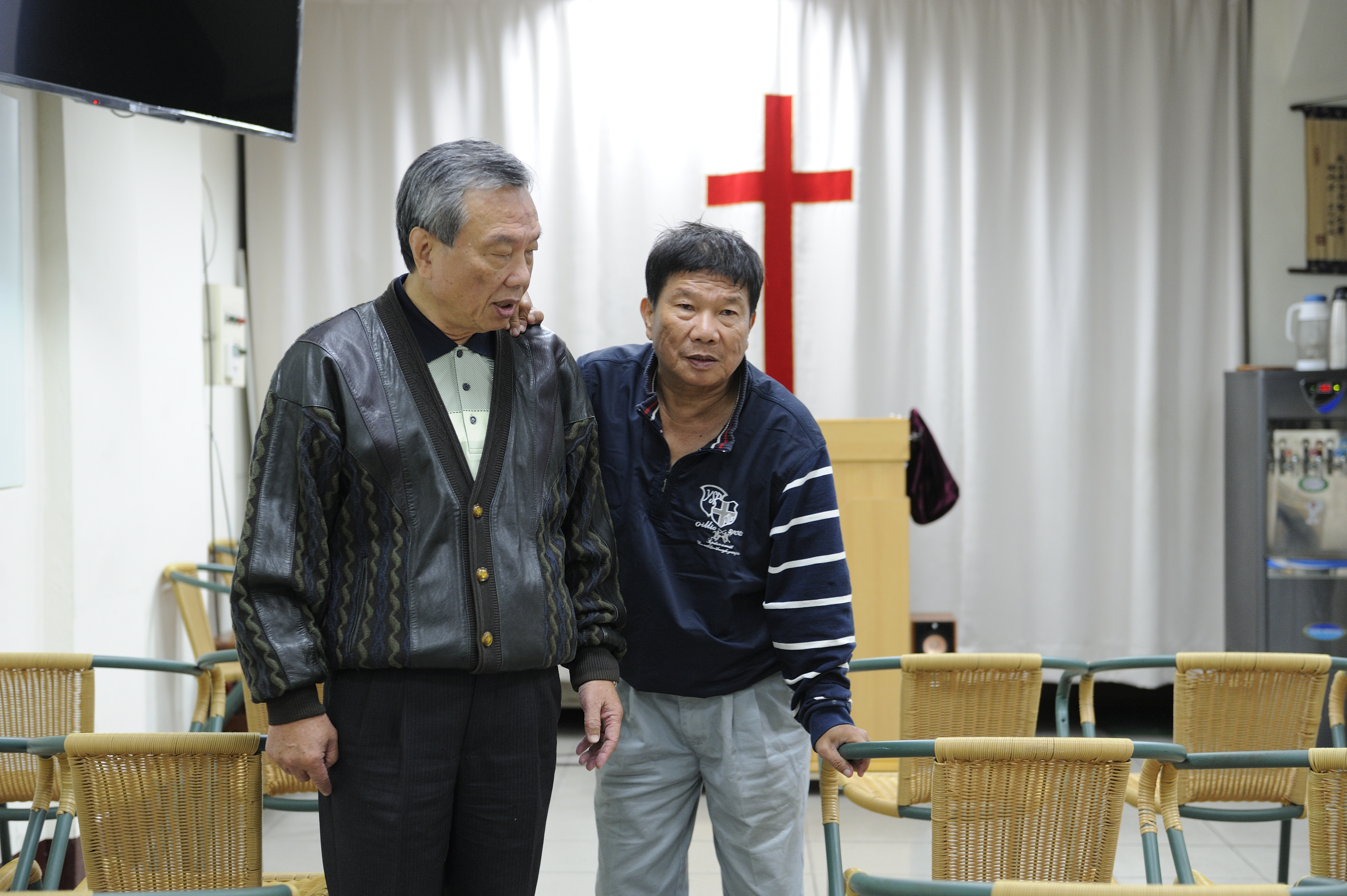 李垂欣（右）在哥哥李東原（左）影響下信教，採訪這日哥哥陪他上教會，行動不靈活的他搭著哥哥的肩慢慢行走。