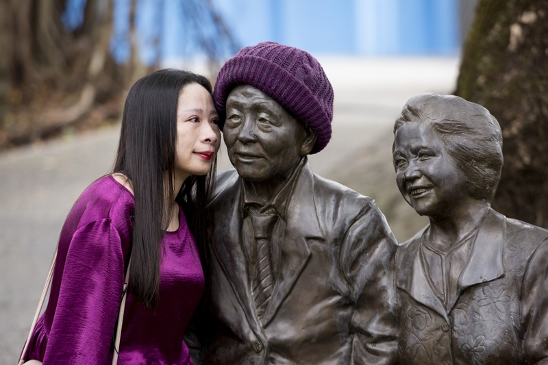 楊恩典（左）的養父養母2013年相繼過世，育幼院打造了兩人的銅像，楊恩典經常回去跟他們說說話。