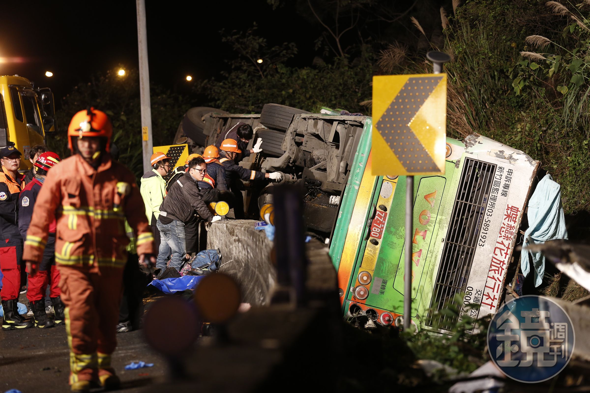 警消在遊覽車翻覆的邊坡仔細搜尋，由於車門被車身壓著，也增加施救難度。