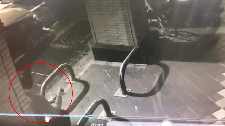 林男坐在路旁的護欄上，不斷轉動手中的警棍，在找尋下手最佳時間點。