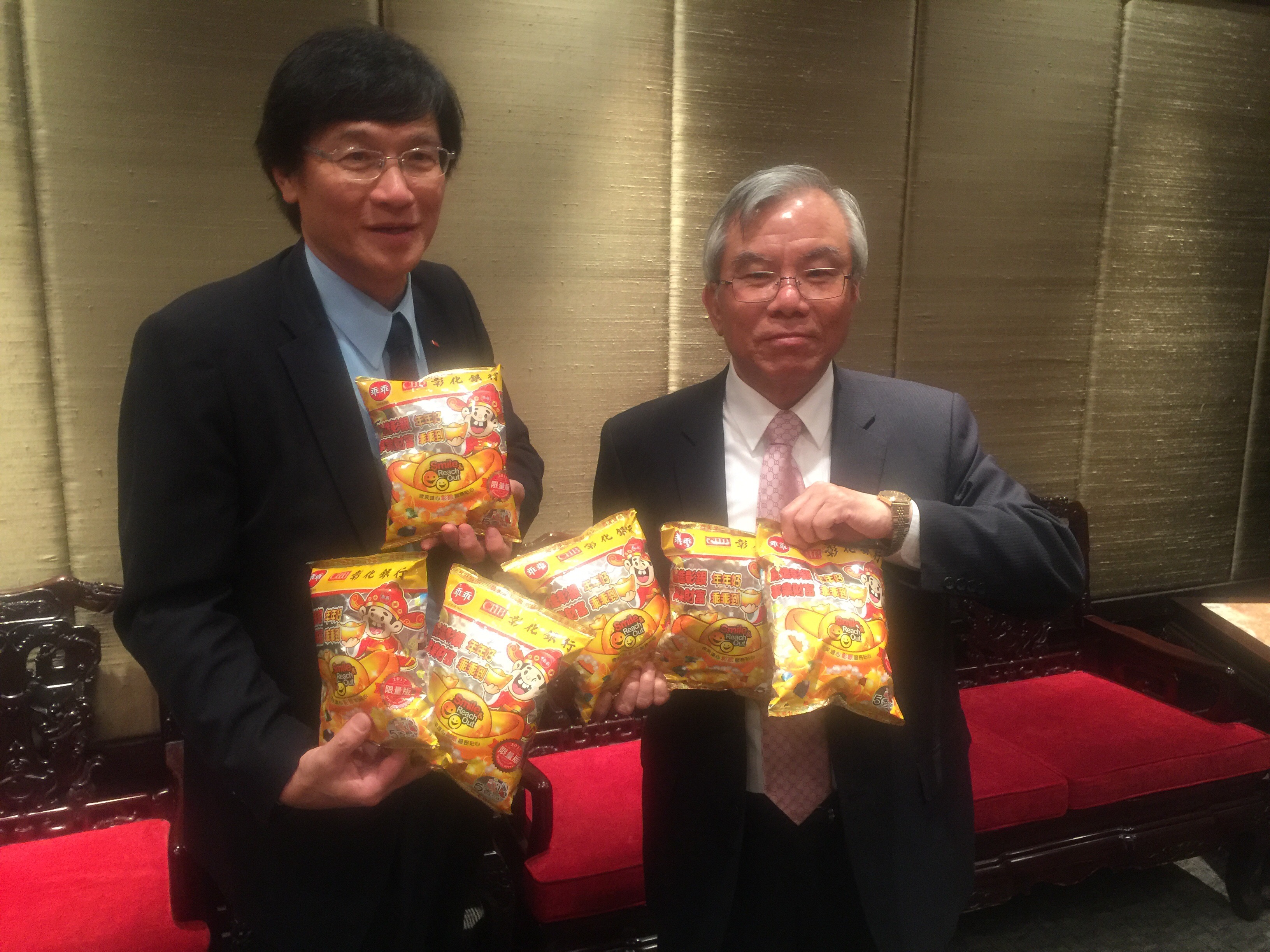 彰銀董事長張明道（右）、總經理施建安（左）拿著今年研發專屬的「彰銀包裝的乖乖」，作為送給客戶的銀行禮。