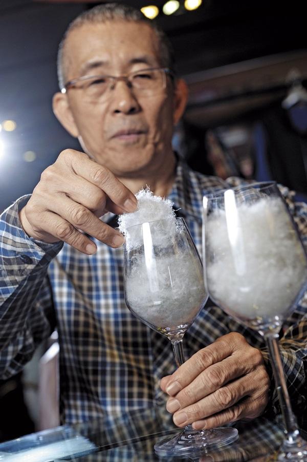 方顯裕是羽毛專家，徒手觸摸就能分辨羽絨比例。左為添加備長炭3D包覆羽絨纖維的蓄熱羽絨。