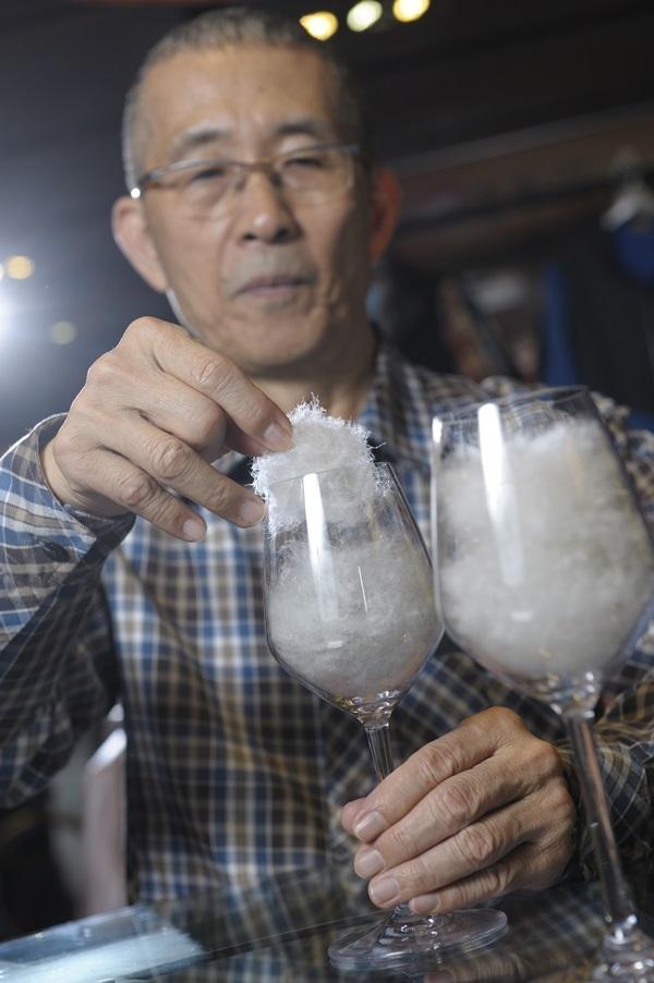 方顯裕身為羽毛專家，徒手觸摸就能分辨羽絨比例，左為添加備長炭3D包覆羽絨纖維的蓄熱羽絨。