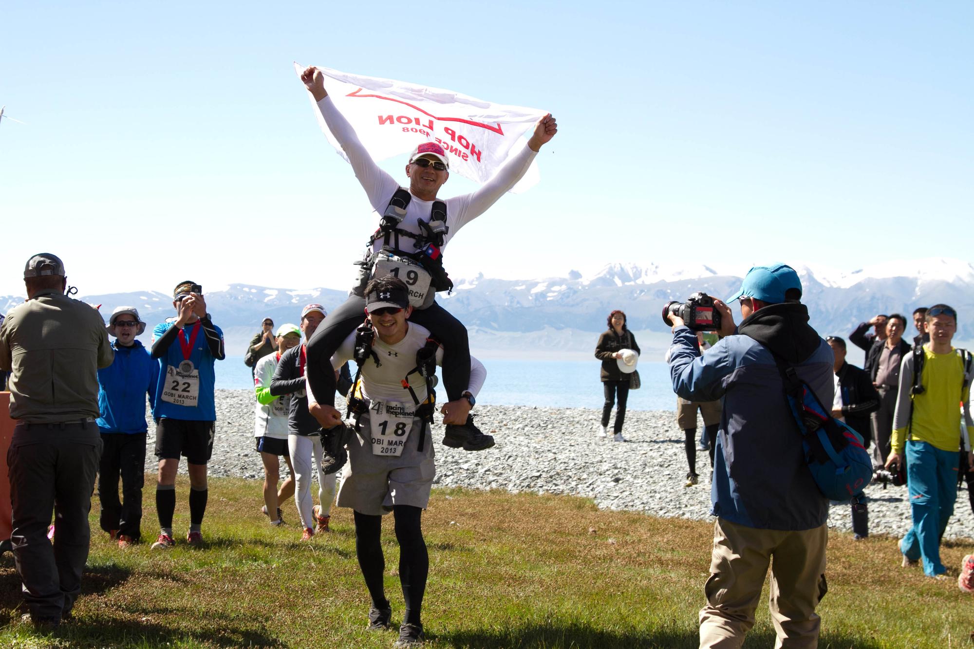 跑進中國戈壁沙漠終點前，陳彥誠把父親陳焜耀扛在背上通過終點線。（陳彥誠提供）