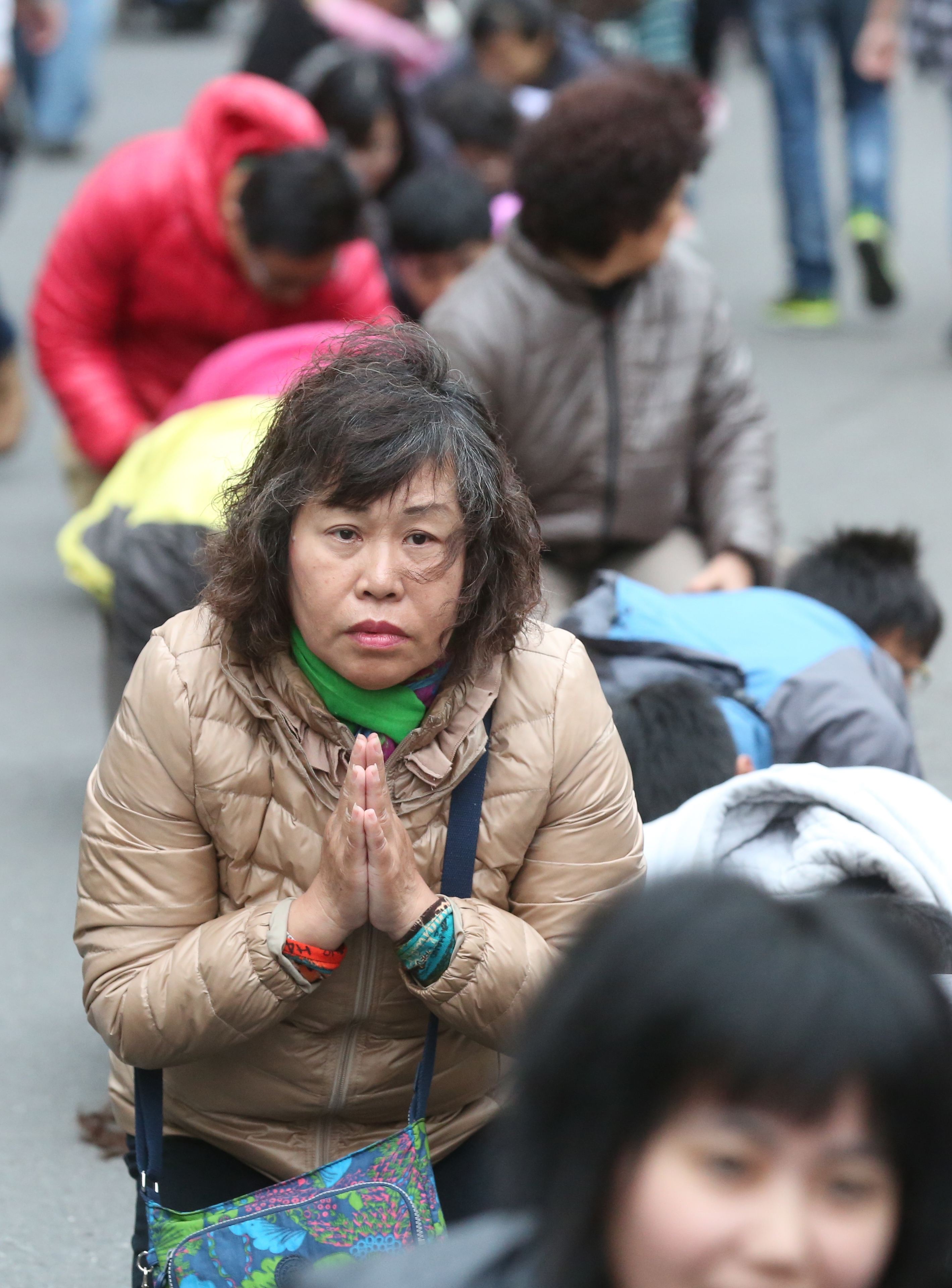  等候鑽轎底的民眾，雙手合十，虔誠地等待媽祖鑾轎到來。