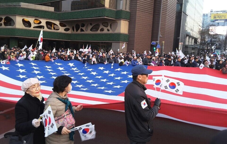 在首爾市廳廣場上，親朴派群眾一起拿著美國國旗，要求重視安保與支持部署薩德，主張彈劾總統全是陰謀。