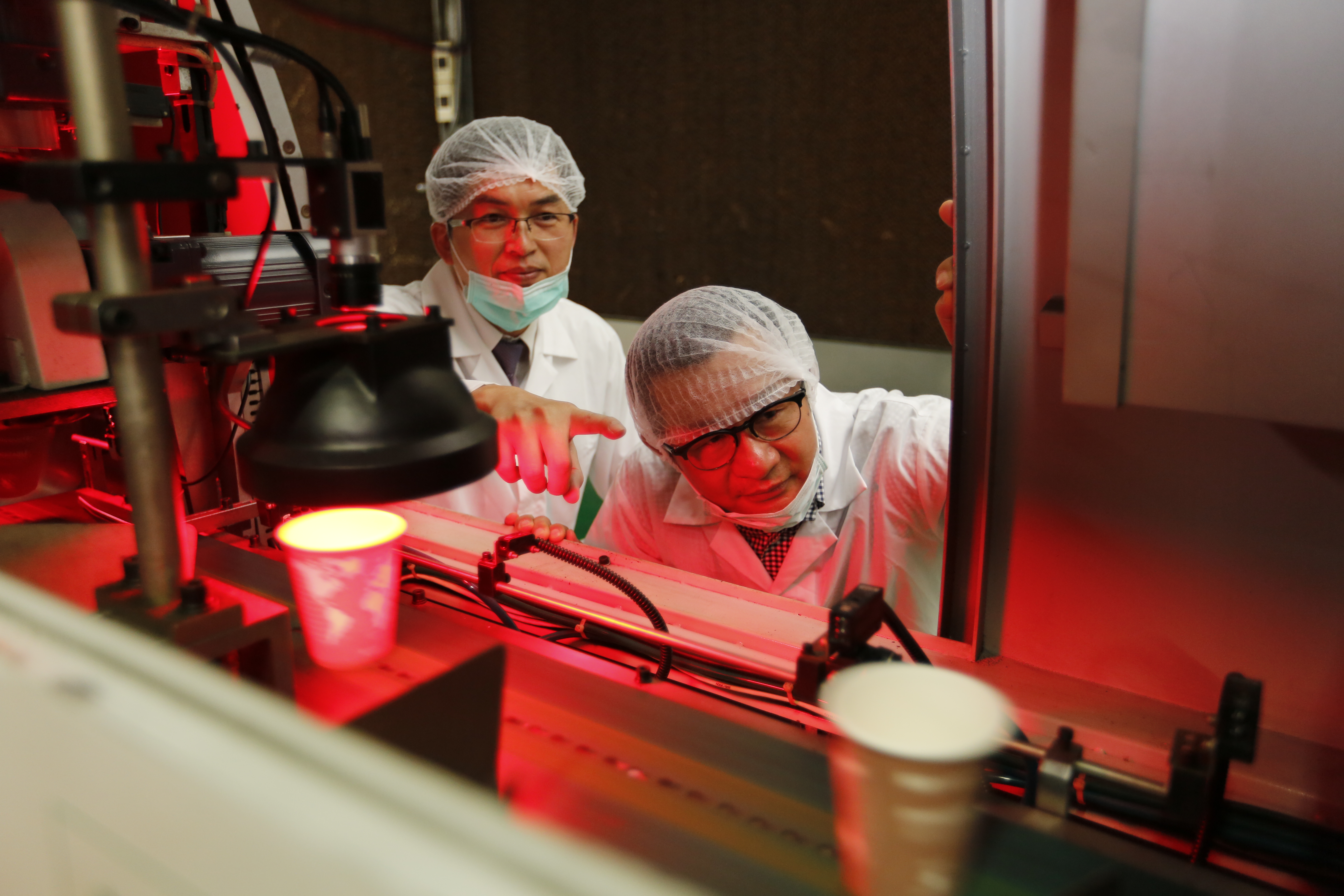 奎達集團董事長林俊賢(右)打造國內生產最多樣化的紙杯廠，圖為自動化紙杯檢測機，可同步執行外觀、形狀、尺寸篩檢與髒汙檢查。