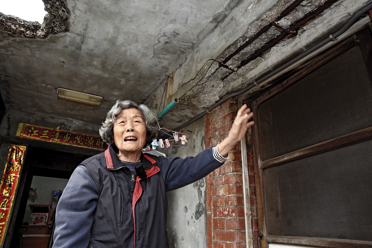 81歲的盧阿嬤聲淚俱下地說，千坪土地被劃為校園用地，卻遲遲未付錢徵收，也不能貸款，讓她沒錢整修老屋，煮飯時還要戴安全帽，避免遭屋頂碎瓦擊中。