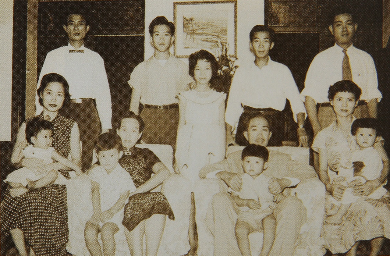 何義與家人在東京下馬住所的客廳。候排右起榮庭、建廷、美慧、政廷、曜廷，前排右起為蔡湘蘋（榮庭妻）、何義、陳肅容、黃素珠（曜廷妻）。前排幼兒自右起為青樺、宗道、宗遠、幸樺。（何家早年難得的全家福，三兄弟何傳(左1)、何義(右2)、何永(右1)，與父親何皆來（左2）及家人合影。（翻攝《台灣前輩企業家：何義傳略》）