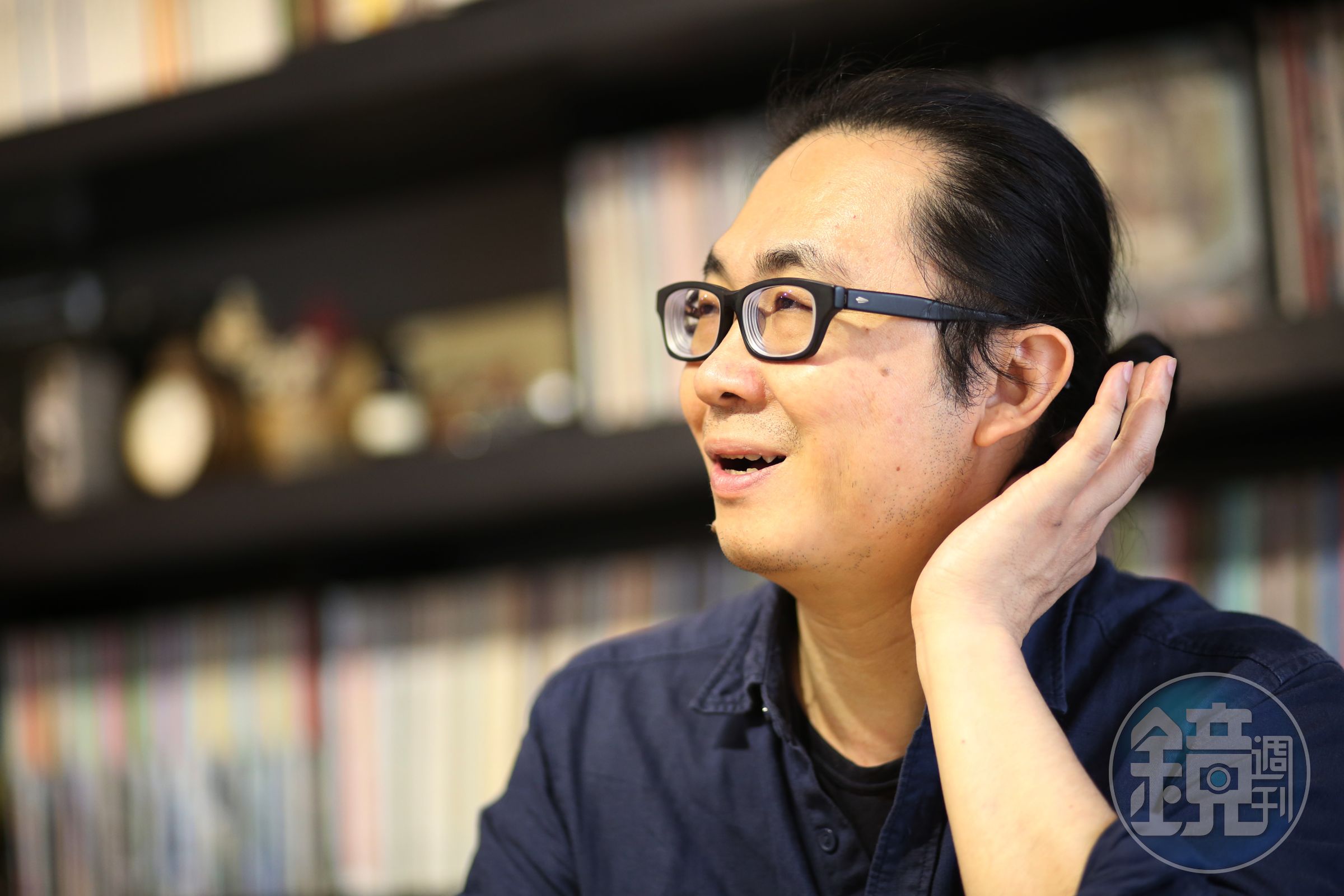 阮光民戴粗框眼鏡、綁馬尾，有藝術家浪漫不羈的氣息。