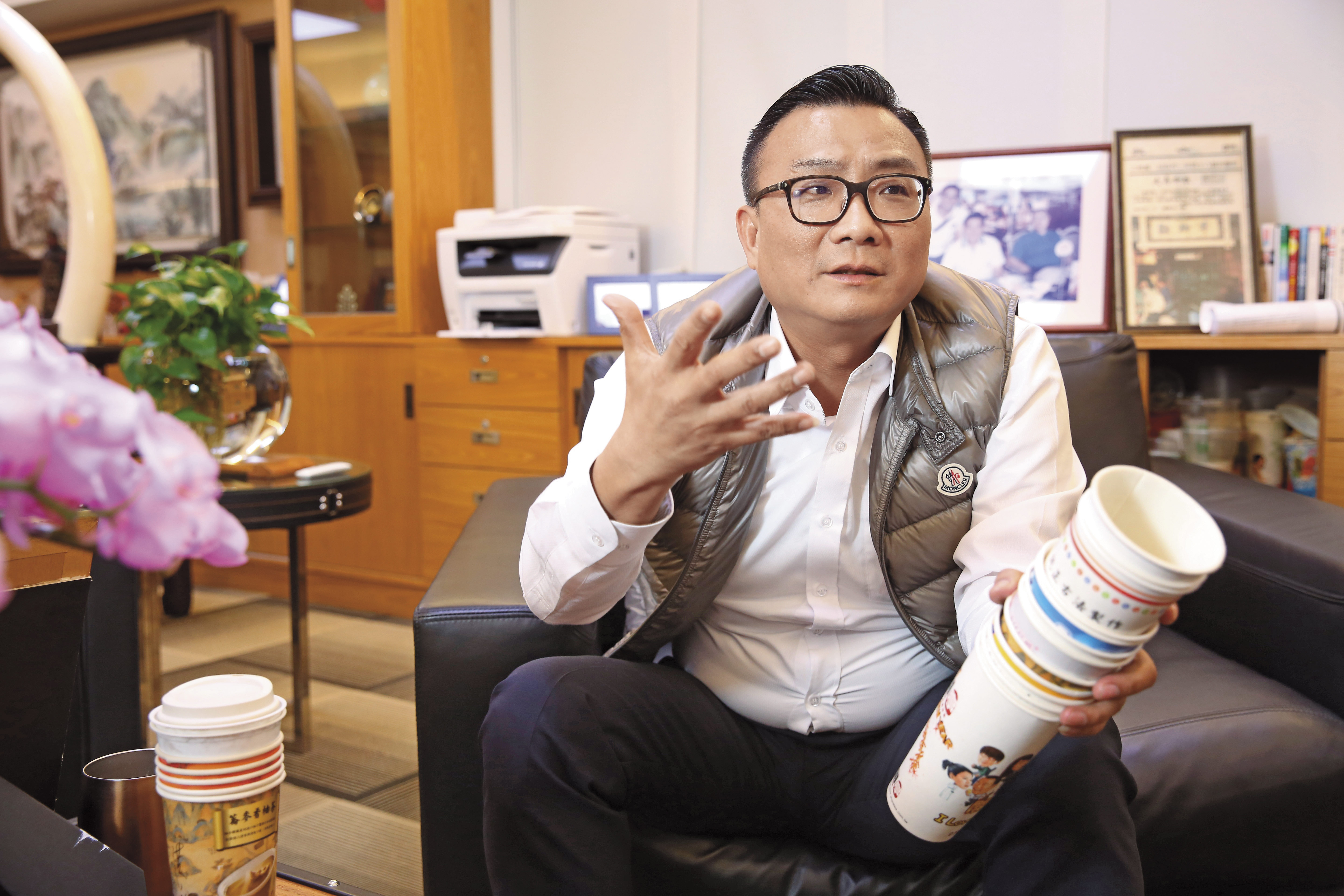 拿著歇腳亭歷代飲料杯，鄭凱隆很驕傲自己首創飲料界的異業結盟，能將杯身當廣告賣，不只可以賺錢，還能提供客人贈品。