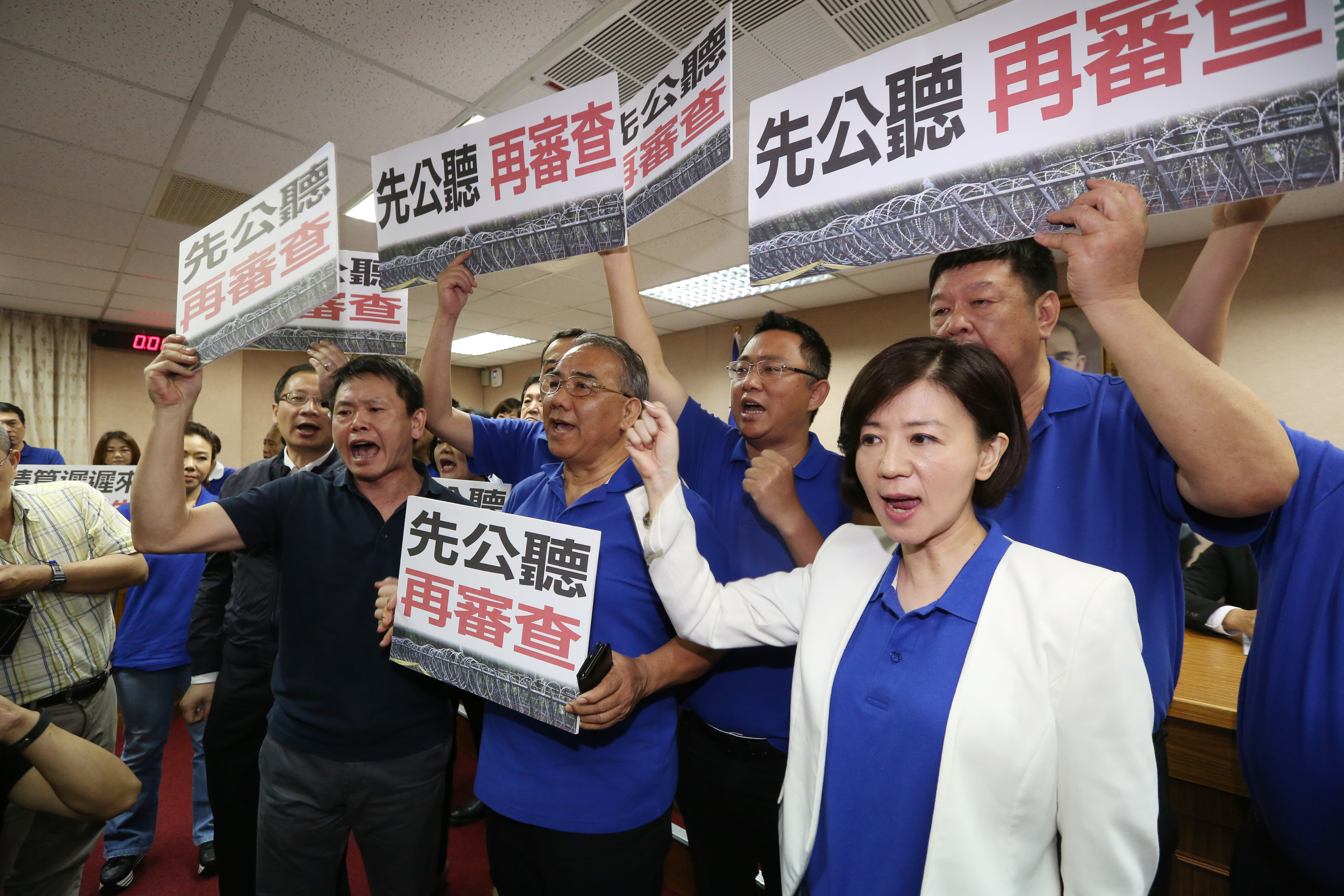 國民黨立委上前包圍主席台，舉抗議標語高喊：「先公聽再審查！」
