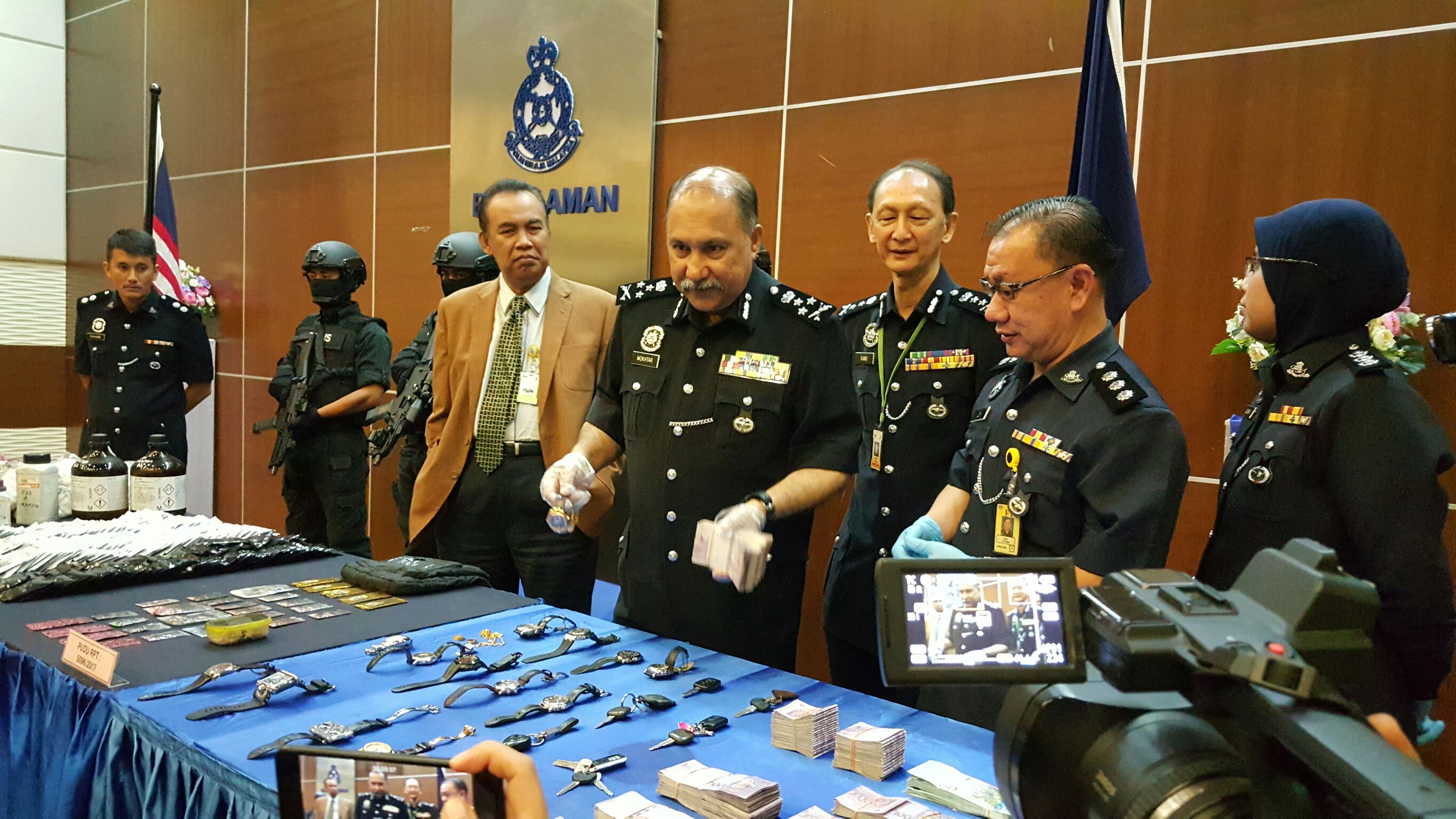 馬來西亞肅毒局長莫達（中立握鈔票者），在記者會上展示本次查緝成果。