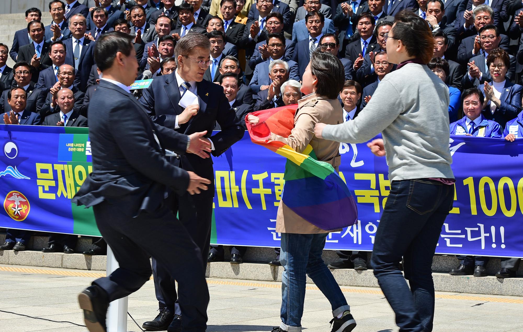 LGBT支持者攜帶採紅旗抗議文在寅（左二）在電視辯論中公開反對同性戀。