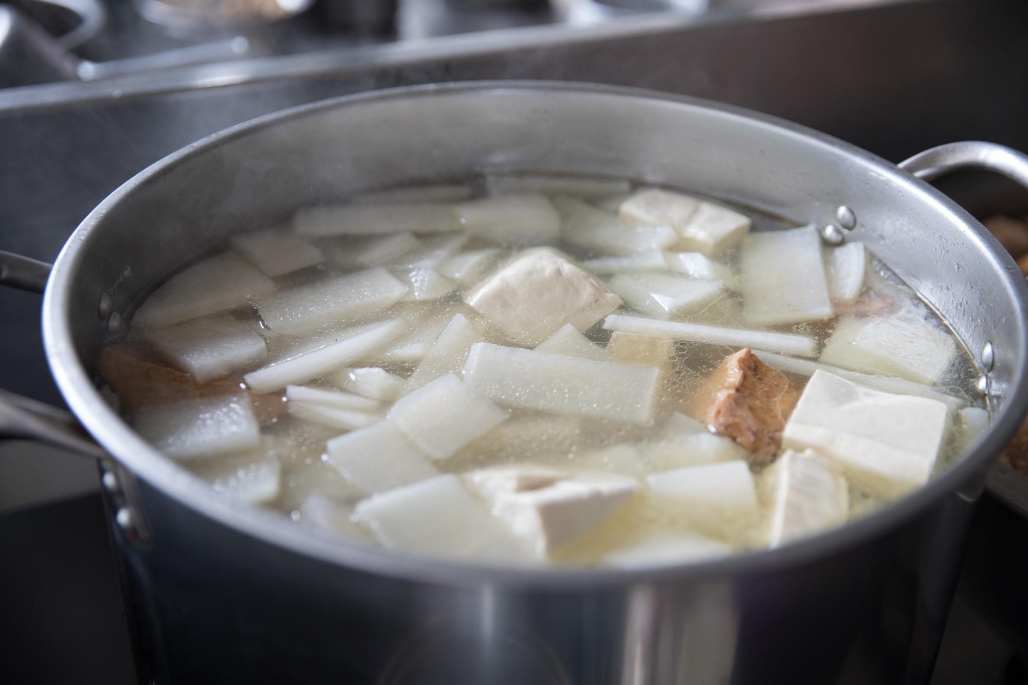 大骨湯裡燉煮著白蘿蔔、嫰豆腐、豬皮等食材，熱氣蒸騰、湯頭鮮甜，為濕涼早晨增添溫暖。