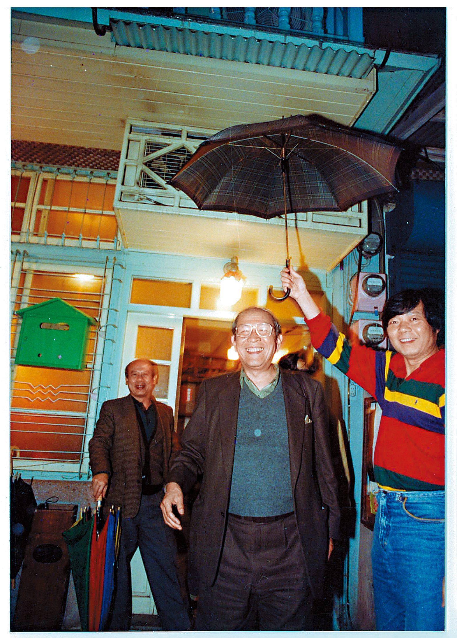 阿才的店一直是黨外運動人士聚集場所，第一代老闆阿才（右）幫台獨聯盟主席黃昭堂（左）撐傘。（余岳叔提供）