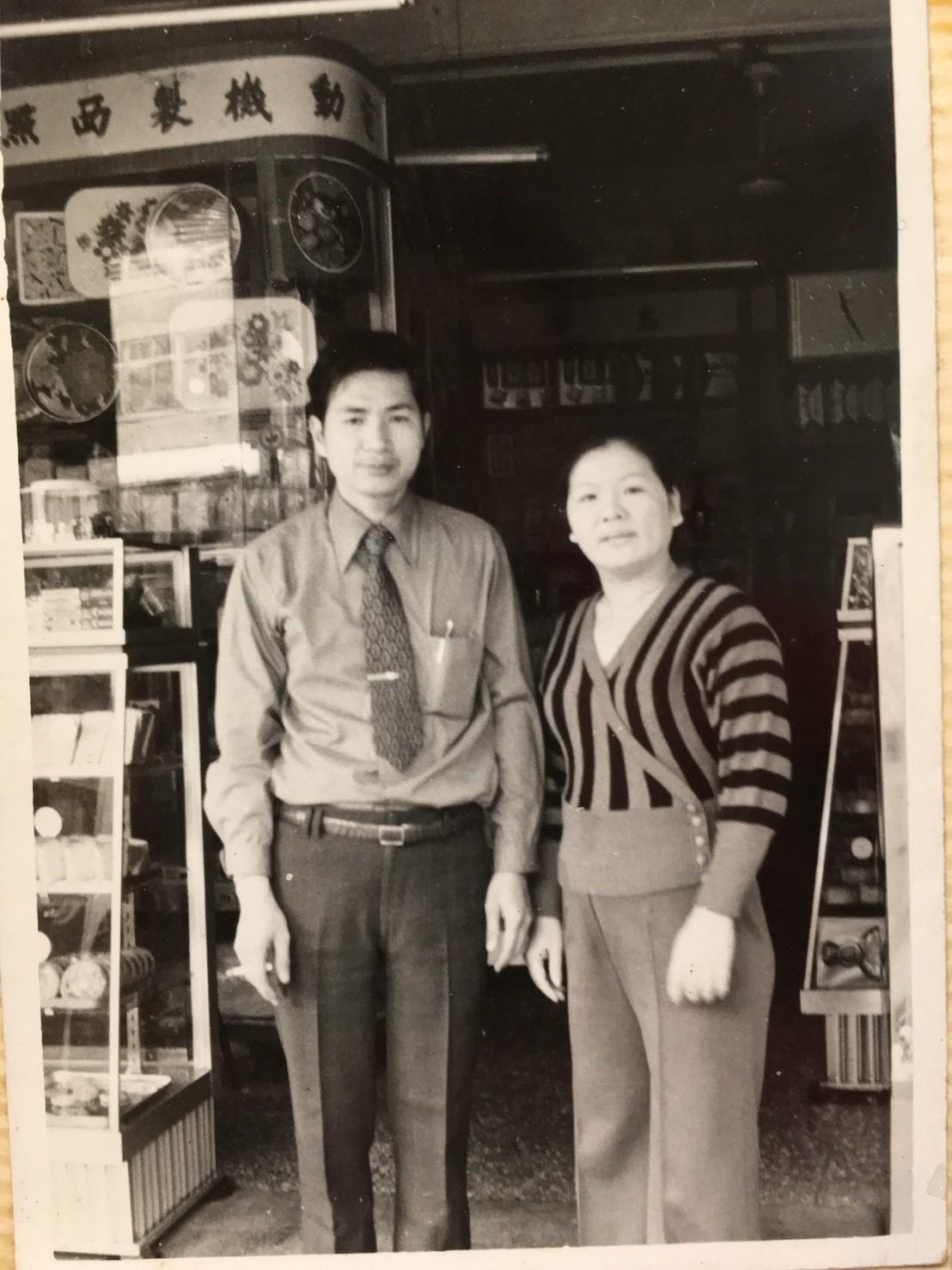 何炳霖小學一年級時，全家遷徙到台北重慶北路開雜貨店兼麵包店，何炳霖的父親何振芳與母親陳採霧在店前合影。（何炳霖提供）