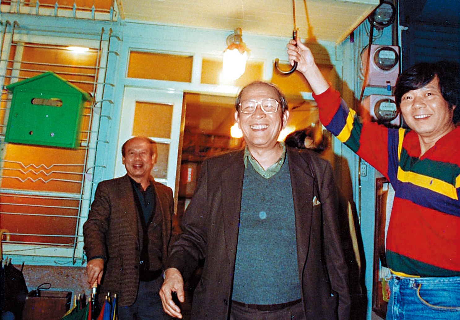 阿才的店一直是黨外運動人士聚集場所，第一代老闆阿才（右）幫台獨聯盟主席黃昭堂（左）撐傘。（余岳叔提供）