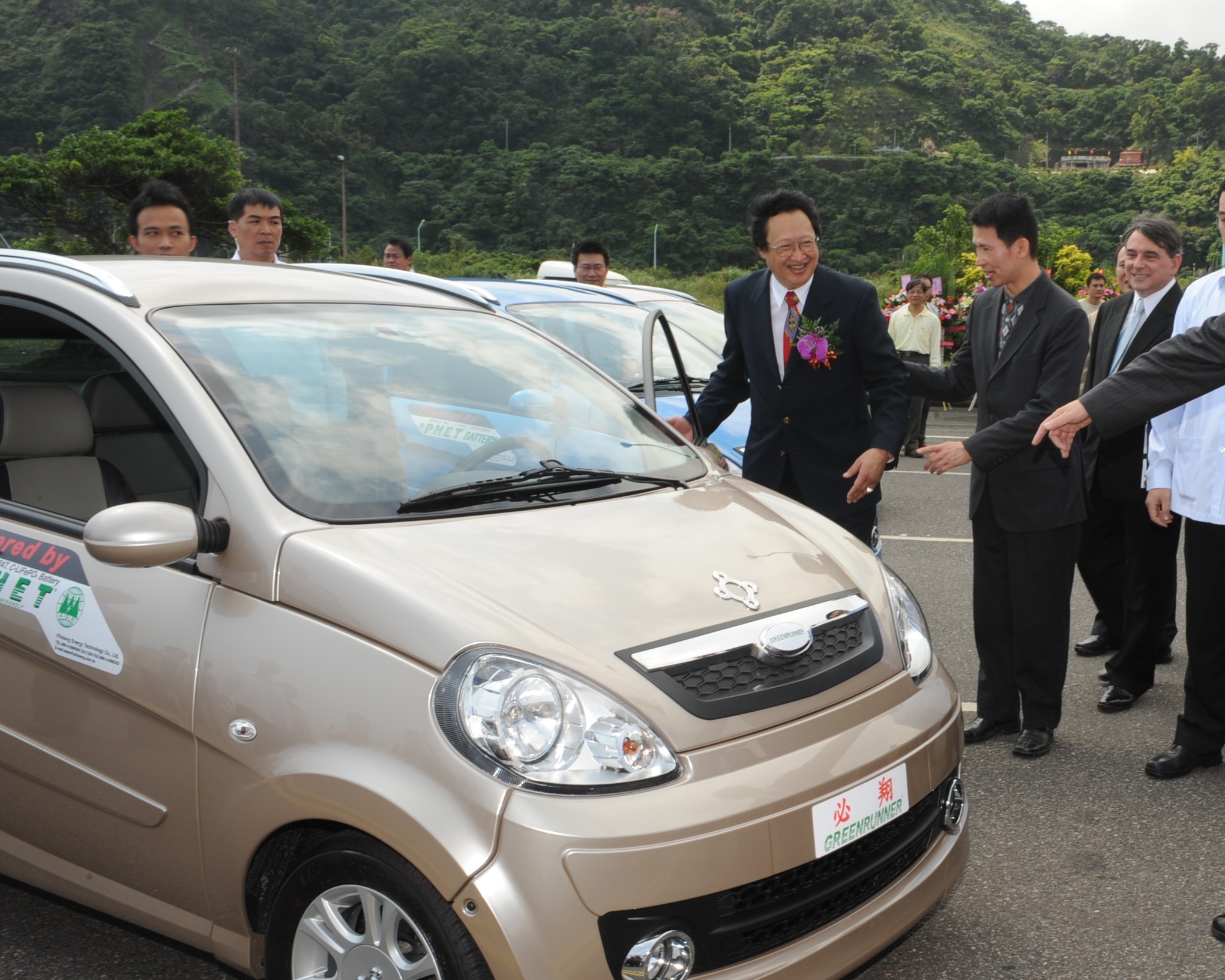 電動車大廠必翔股價連番重挫，董娘伍蔣清明今日出境遭攔。圖為創辦人伍必翔（開車門者）介紹自家電動車。（翻攝自行政院全球資訊網）