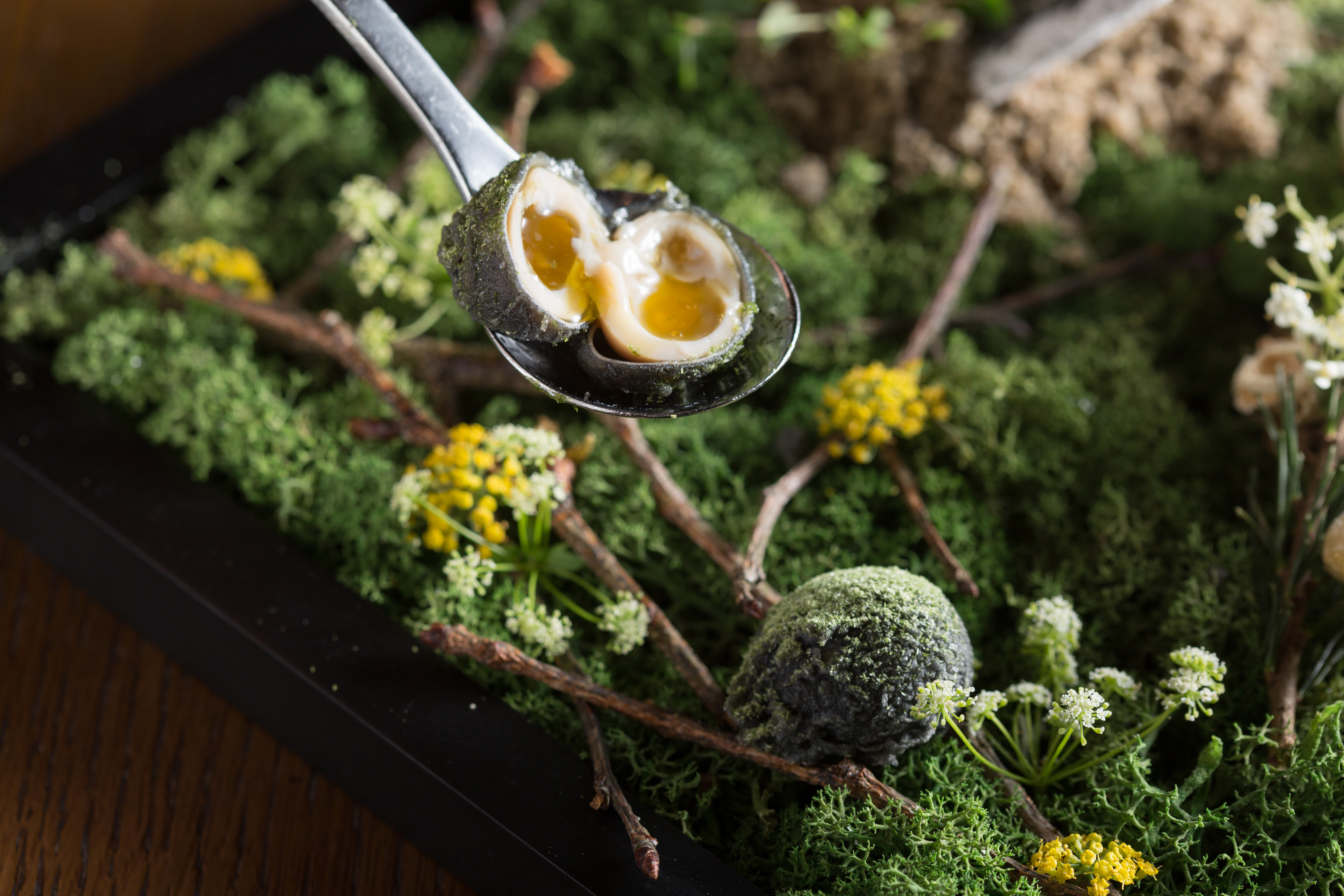 以醬油、刺蔥醃過的「炸鵪鶉蛋」裹上竹炭粉後酥炸，咬開是溏心蛋質地。這是餐會中的一道菜。