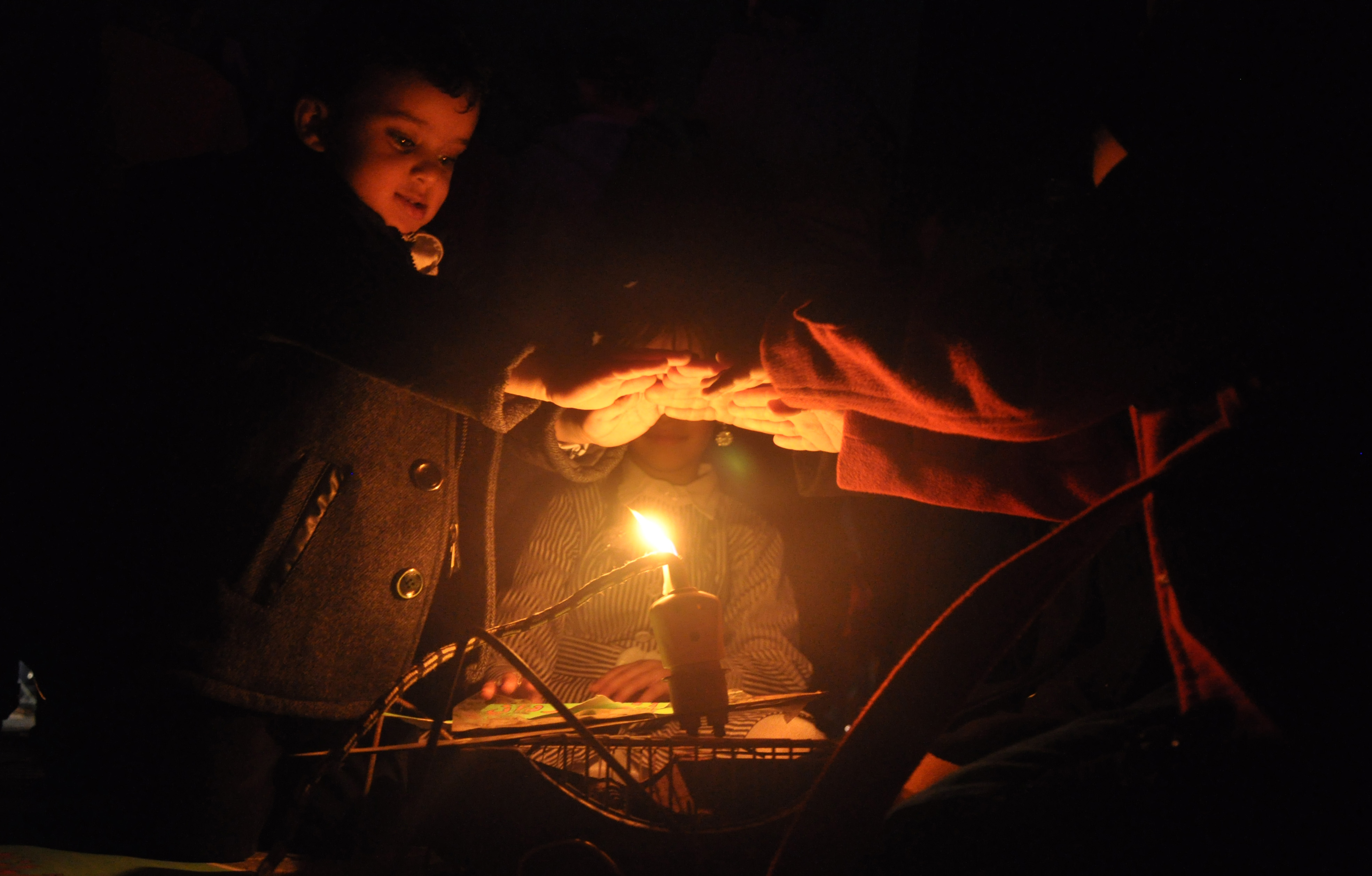 加薩地區極度缺電，孩童在夜晚僅靠一根蠟燭取暖。