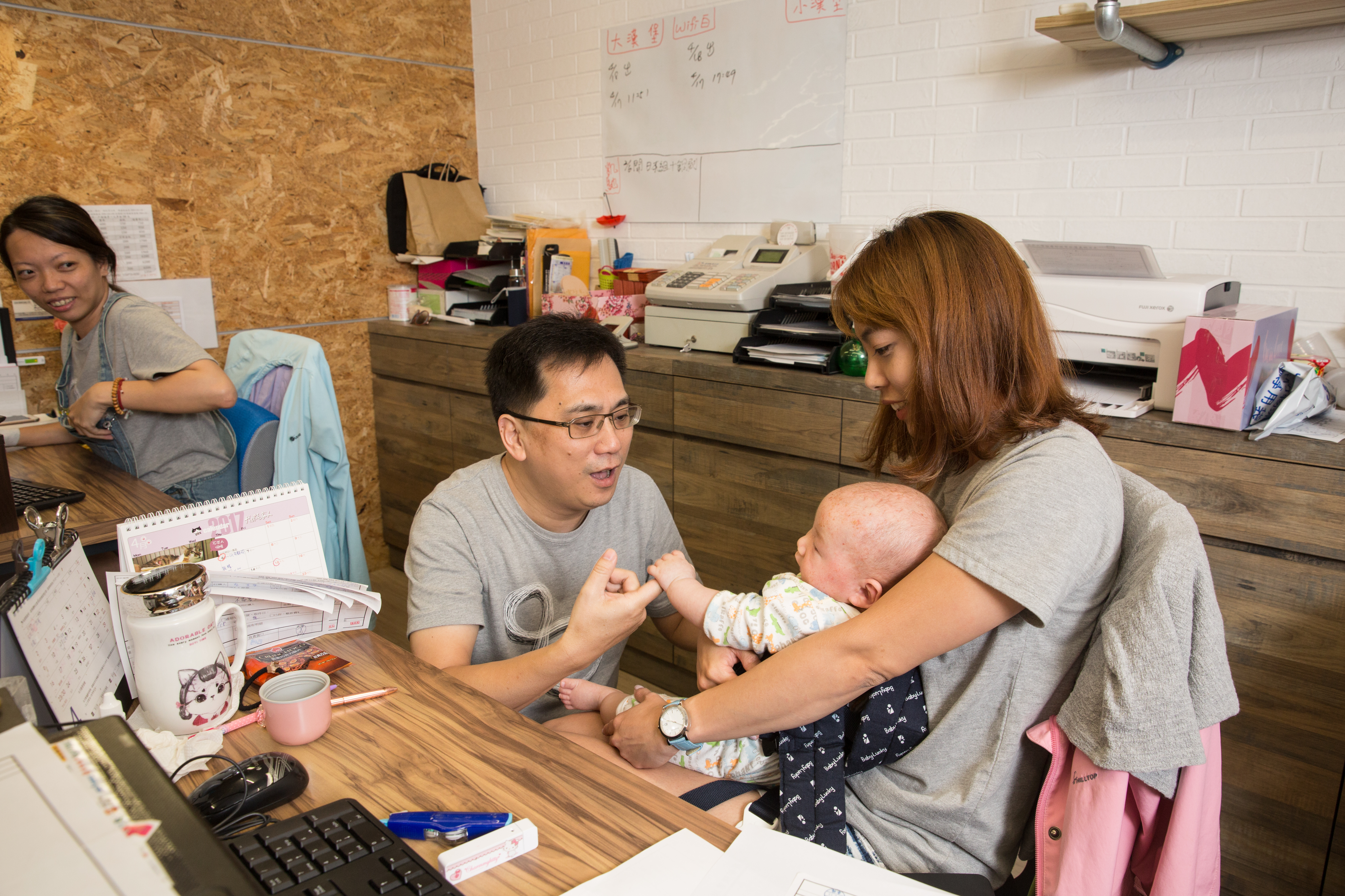 因父母自小離異，渴望家庭完整的陳延昶（左二），正逗弄顧客的小孩。