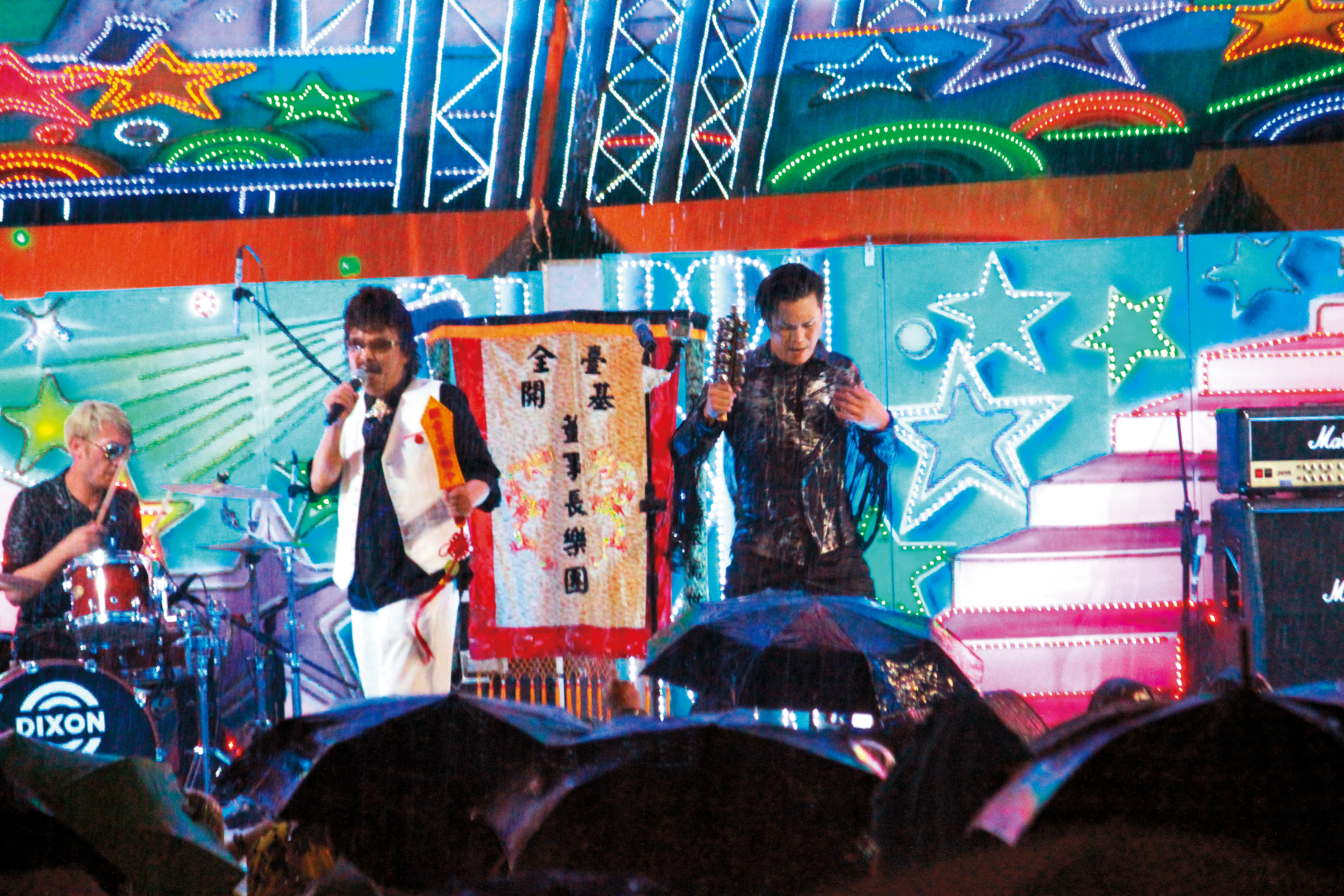 董事長樂團阿吉（右）與「台客始祖」黃克林台上PK，不畏颱風天全身溼透，滿足底下撐傘的觀眾。（角頭提供）