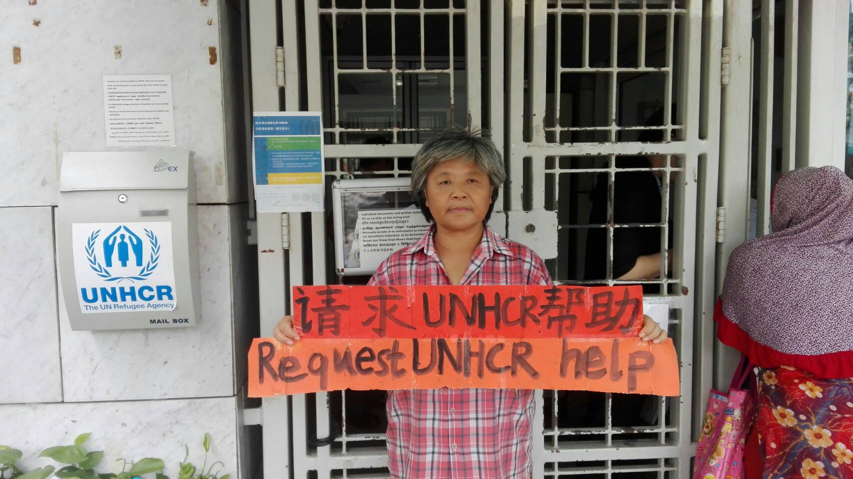 滯留曼谷的中國籍難民張淑鳳，在聯合國難民署前舉牌，抗議未受到妥善安置，並希望能引起往來官員的注意。（攝影：Jack Huang）