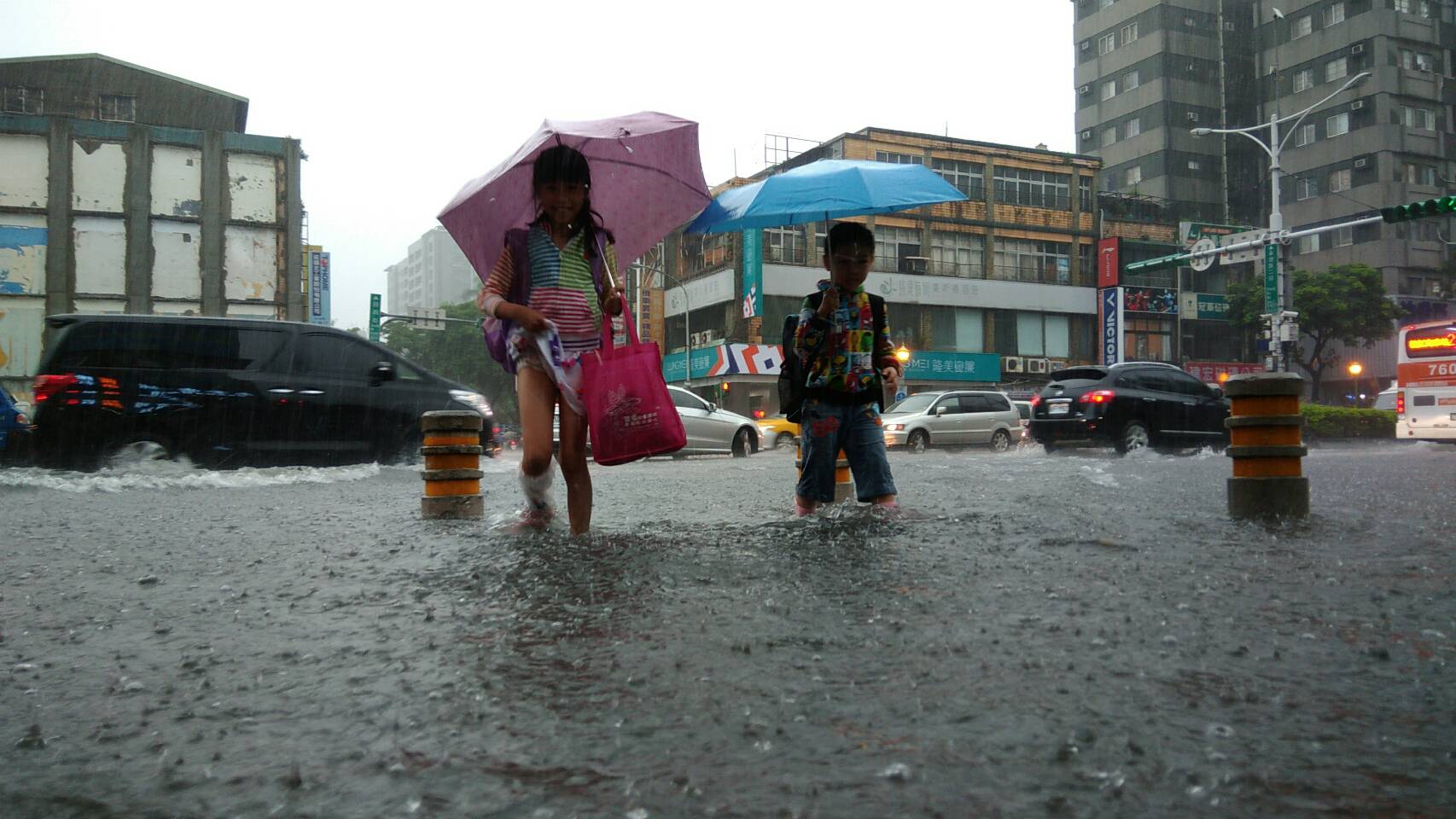受到梅雨鋒面及西南氣流影響，北台灣處處淹水，中午放學的學童必須涉水過馬路，圖為台北市承德路。