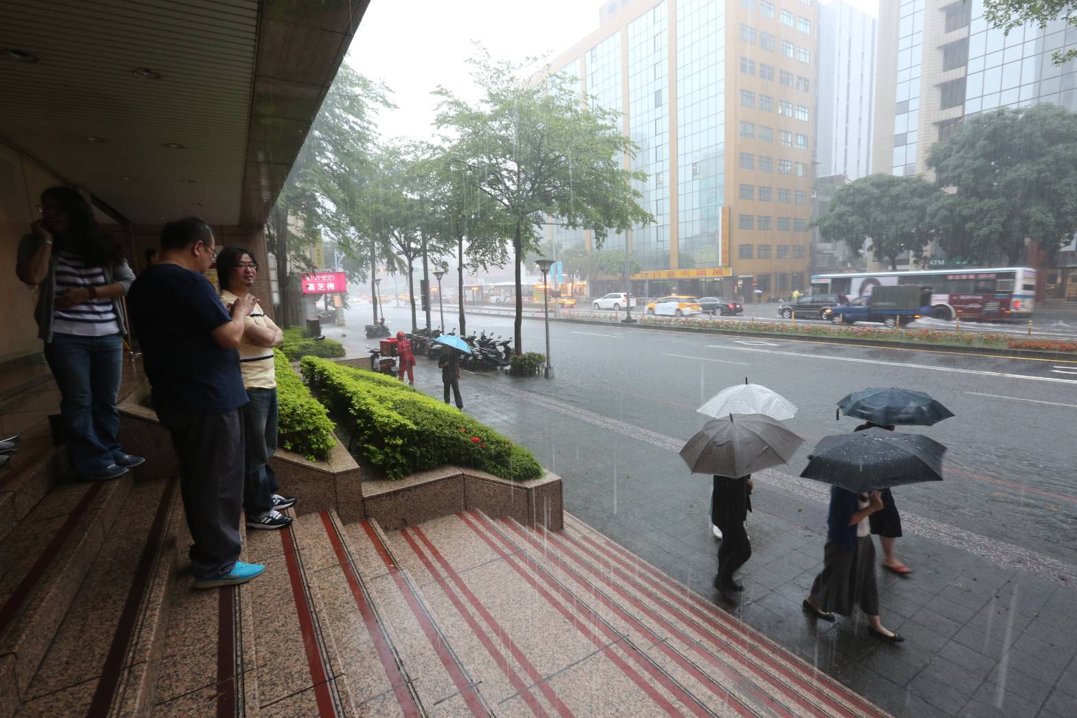 大雨讓不少路人進退兩難，不趕時間的民眾，乾脆到高處避雨。