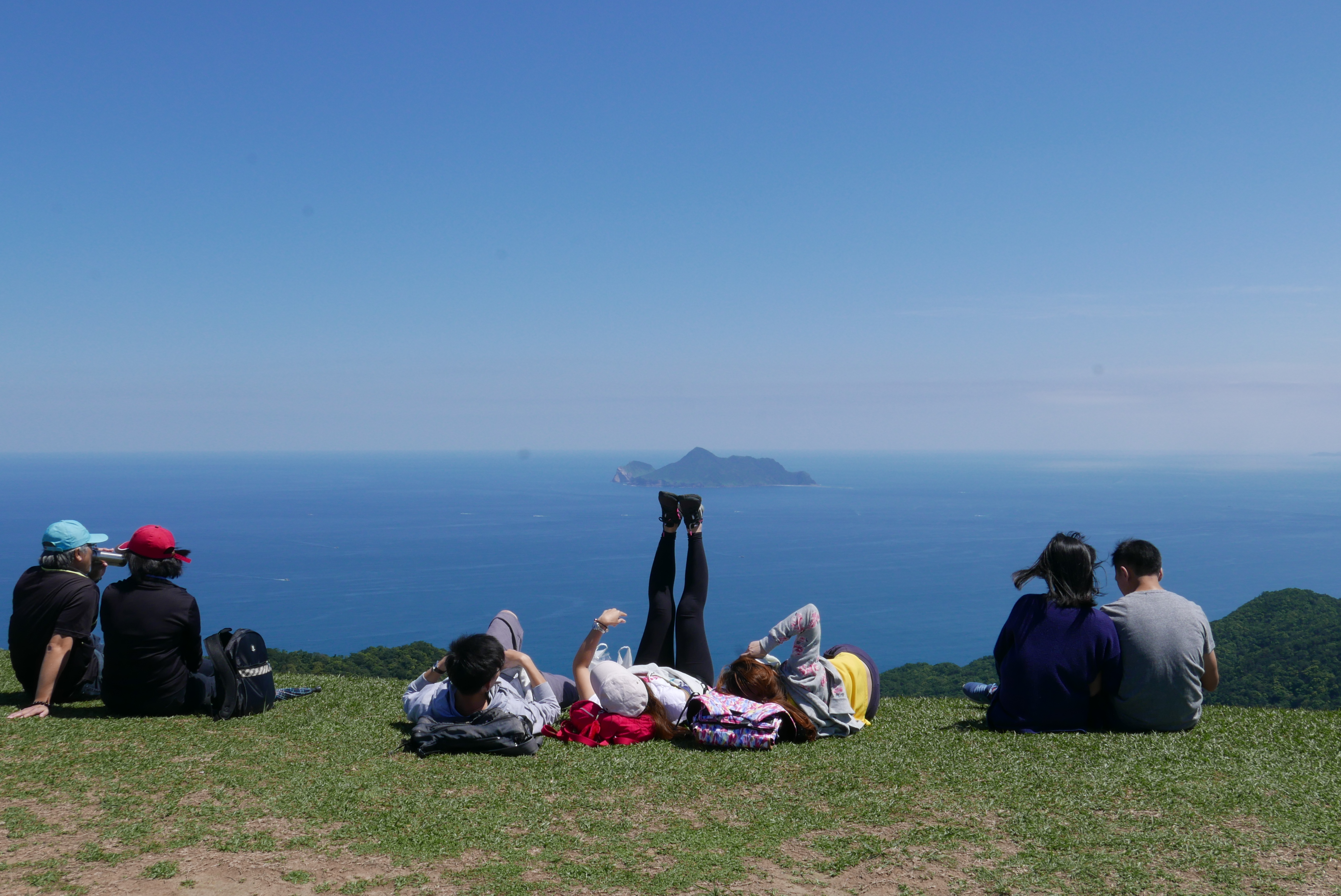 在桃源谷上，許多人坐在山頭上觀賞龜山島海景。