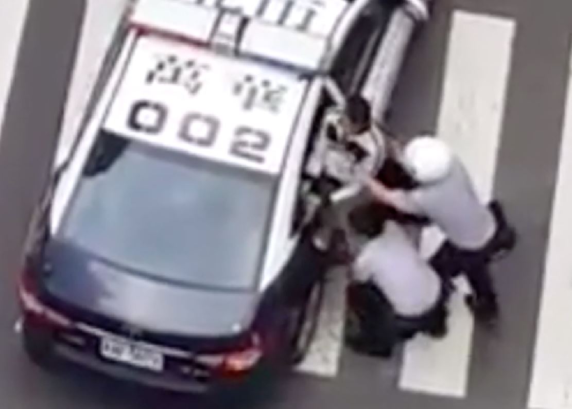男子抵死不上車，員警最後只好合力將他抬起，塞入車內。