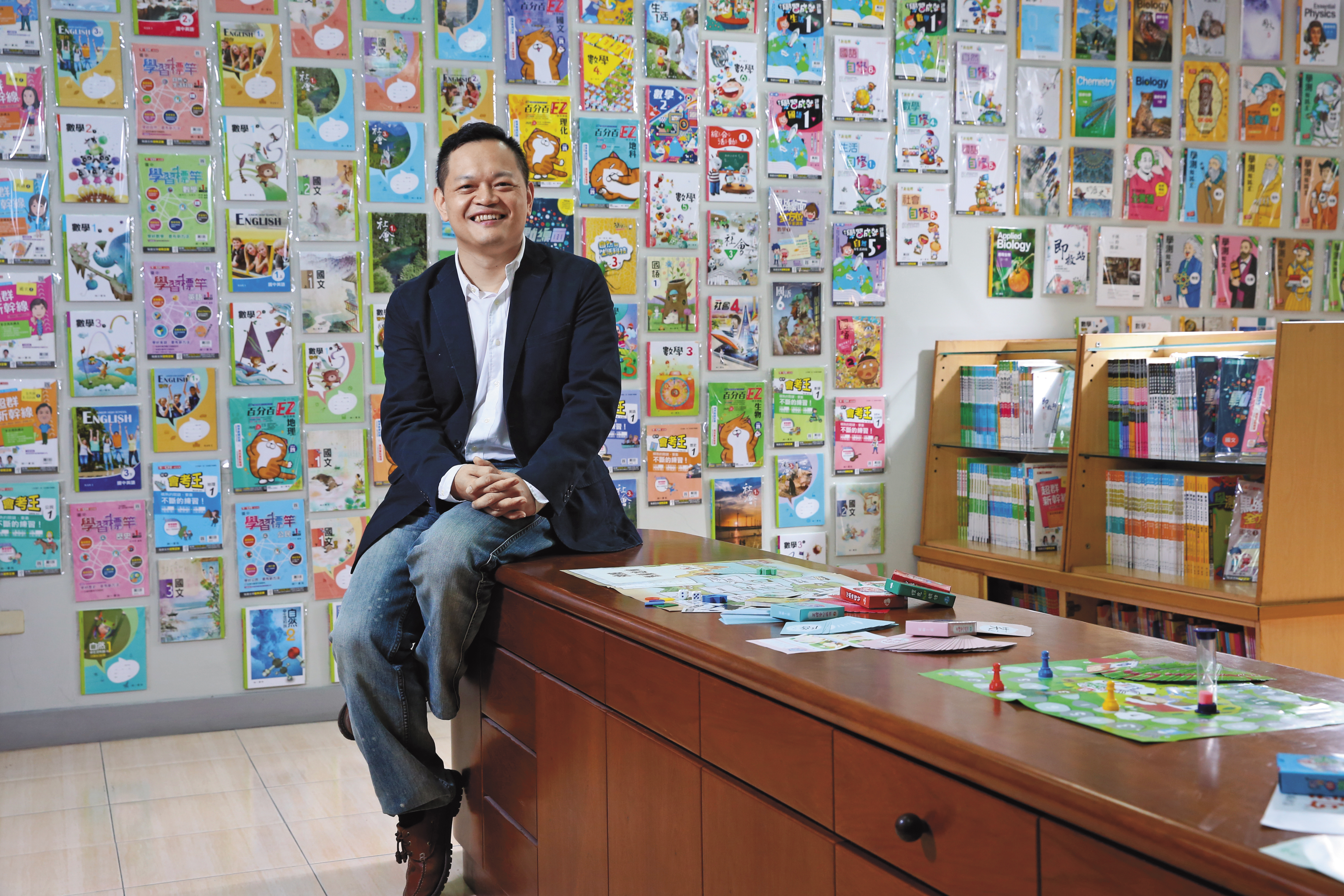 41歲的南一書局總經理蘇偉銓，從小在參考書堆中長大，背後的參考書牆是南一今年的部分出版品。