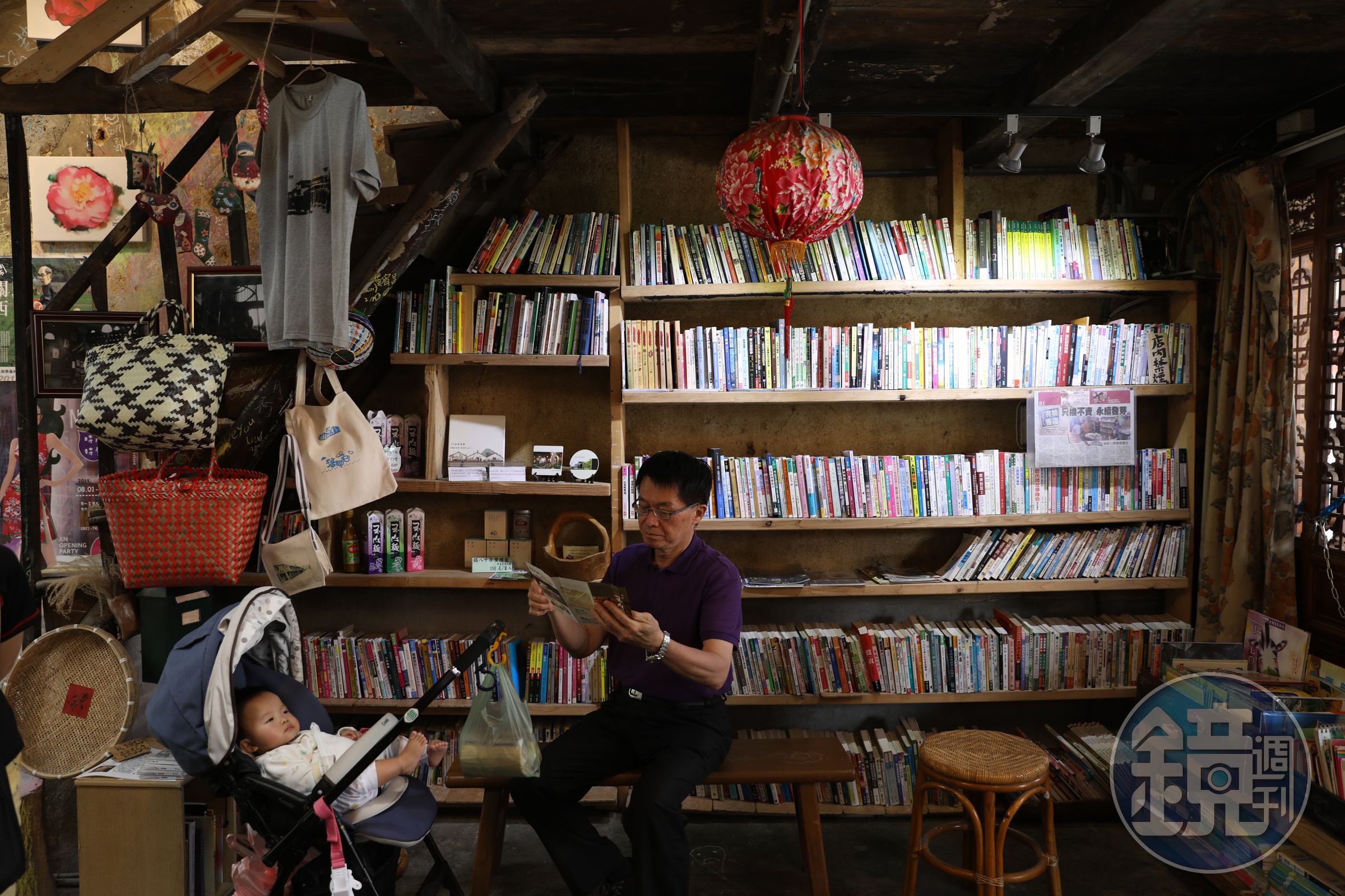 阿伯坐在板凳上看書，像是在自家書房般自在。