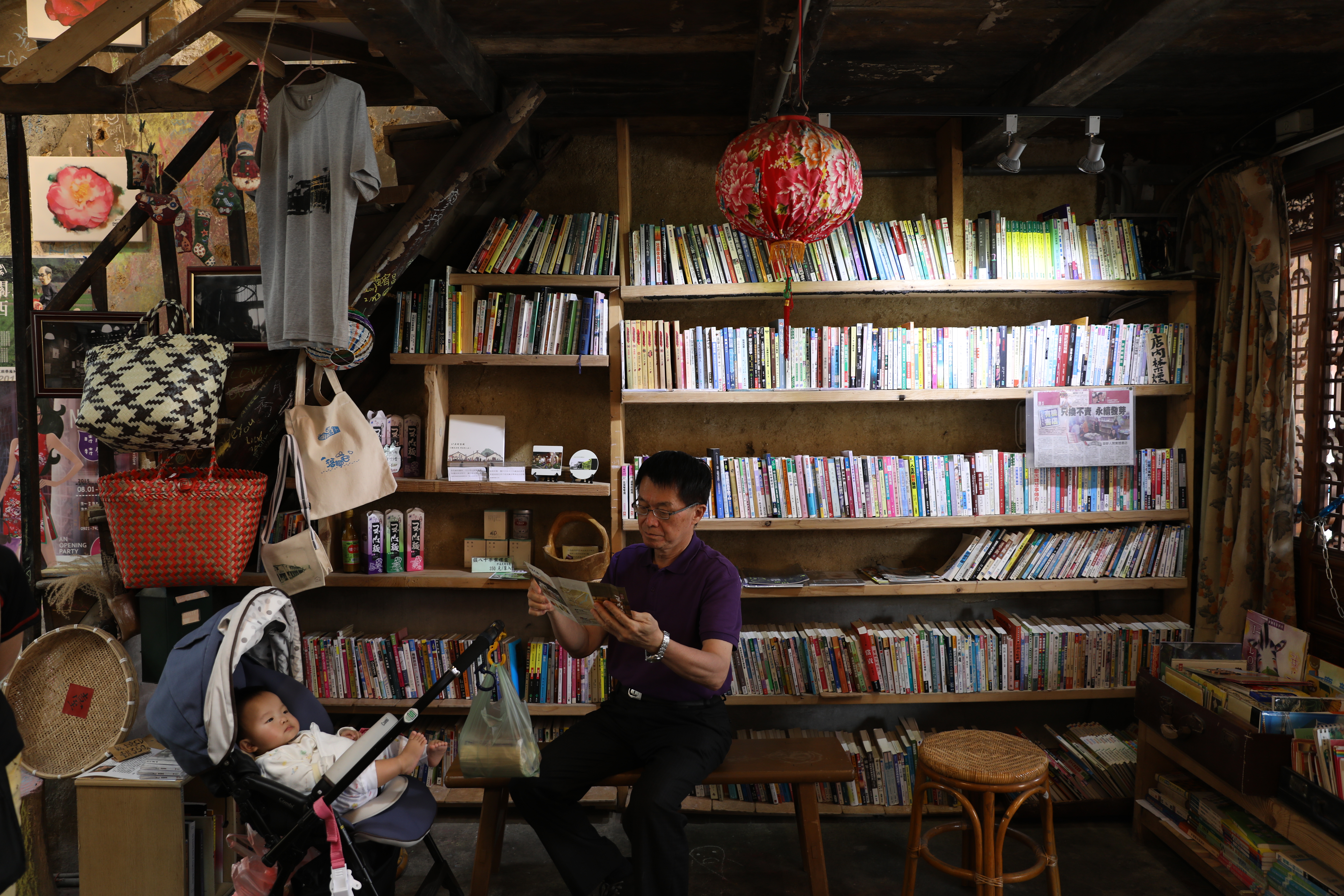 阿伯坐在板凳上看書，像是在自家書房般自在。