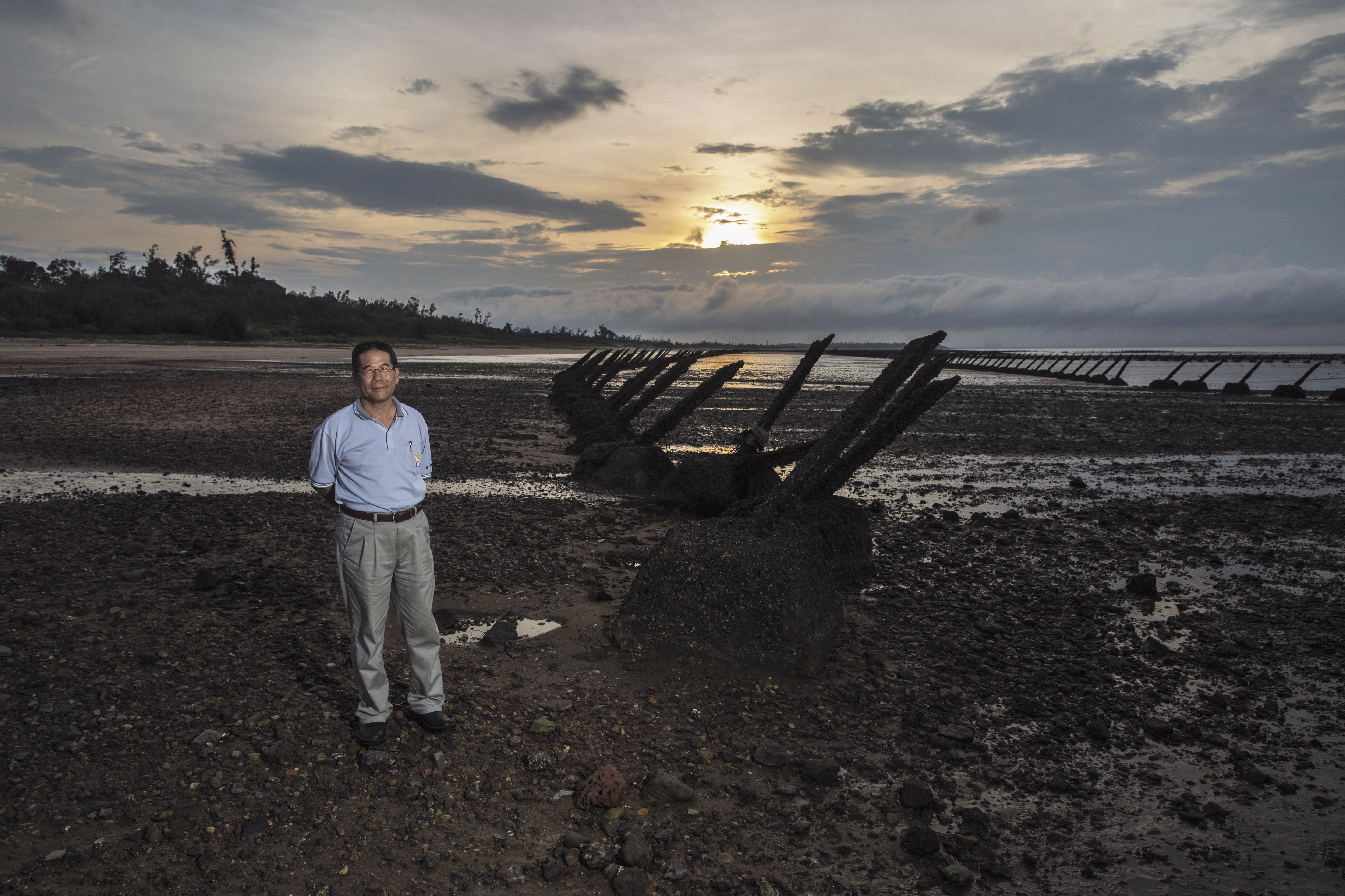 翁明志站在仍布滿軌條砦的嚨口海灘，說起戰地前線金門在嚴格軍事管制下的生活。