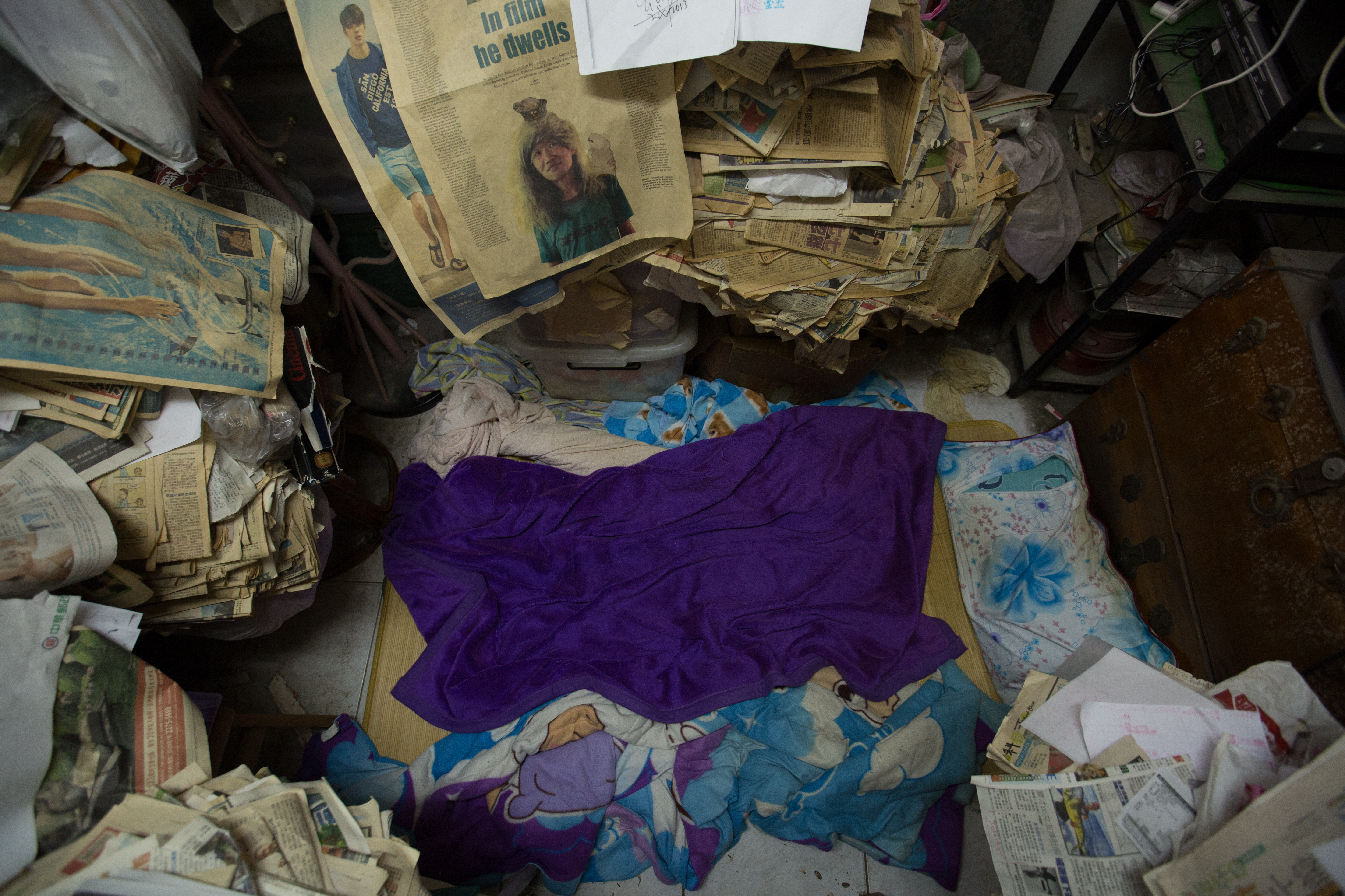 睡覺的地方空間很小，地上的一張毯子旁全都是自己搜集的報紙。