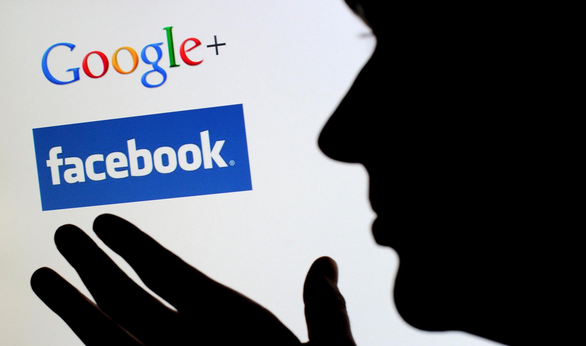 用戶對著電腦螢幕中Google+和Facebook的商標符號。(東方IC)