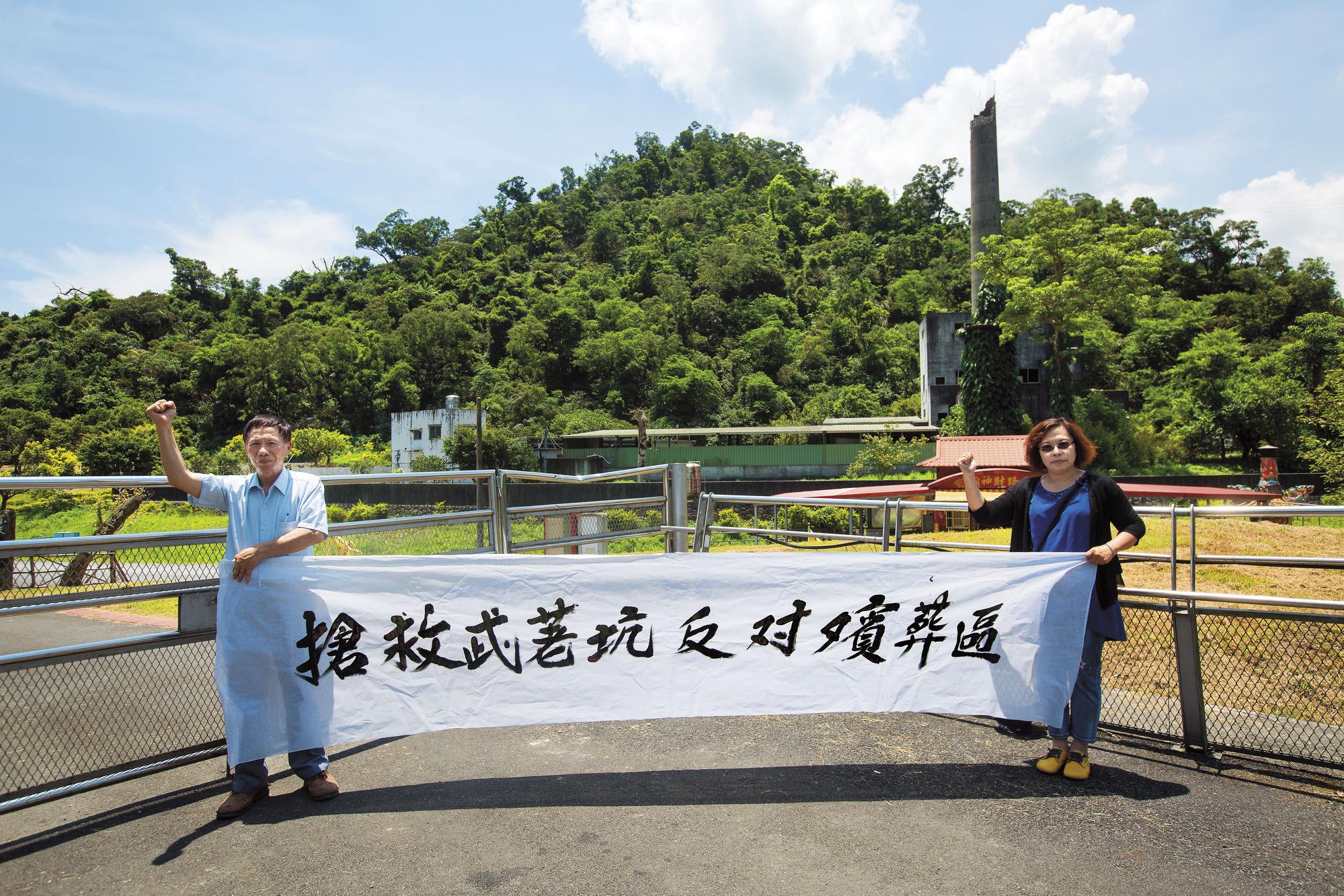 吳錦惠(右)與林連蒼(左)在殯葬區預定地前拉起白布條抗議。