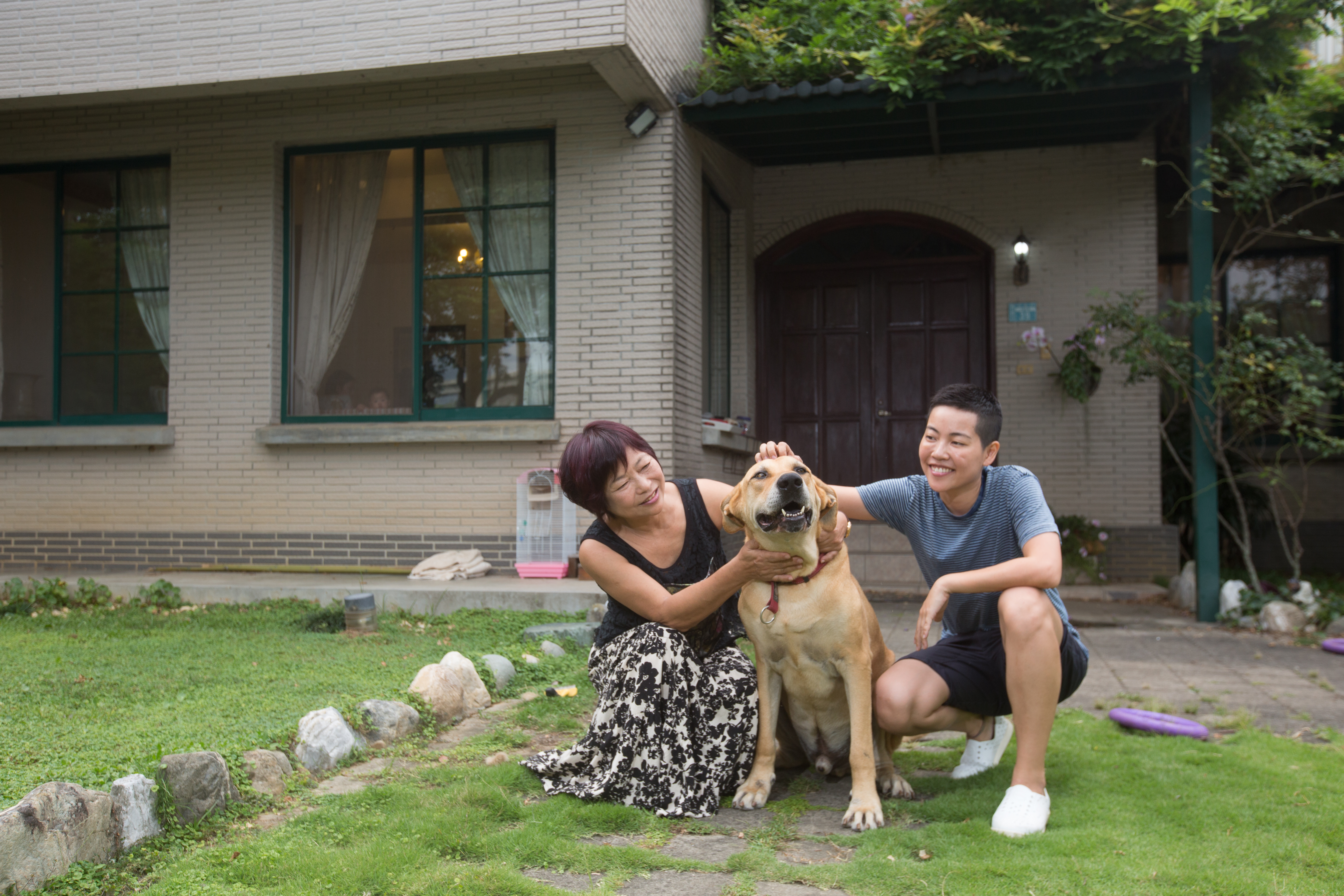 吳沁婕（右一）與媽媽宋慧勤（左一）在庭院合照，大狗史酷比是流浪犬，流浪到吳沁婕家時很瘦。