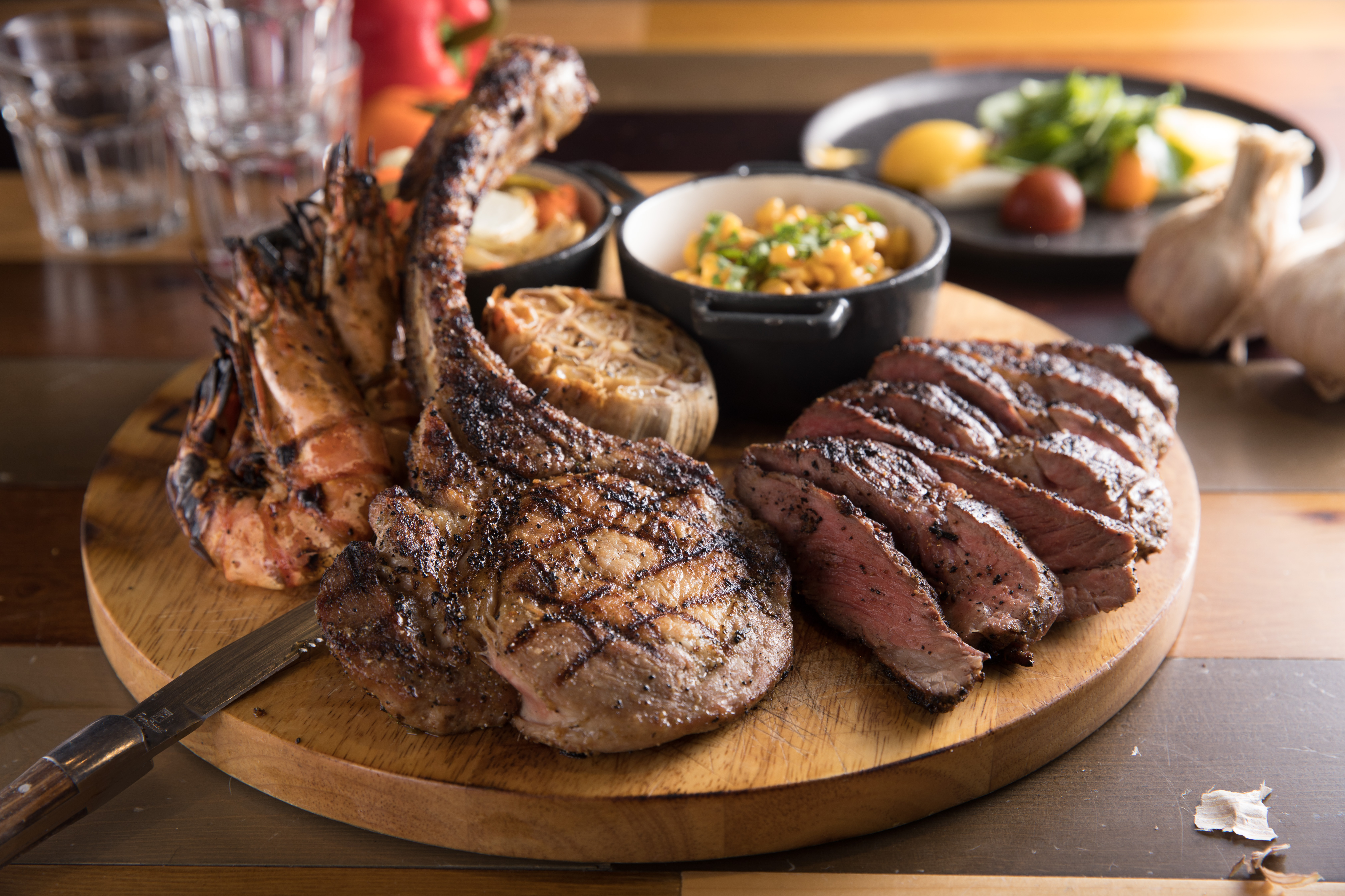 「八百壯士肉搏大拼盤」包含戰斧豬排、丹佛牛排以及大草蝦，搭配季節炭烤蔬菜、墨西哥風味烤玉米粒、烤蒜頭，分量適合3到4人共享。（2000元／份）