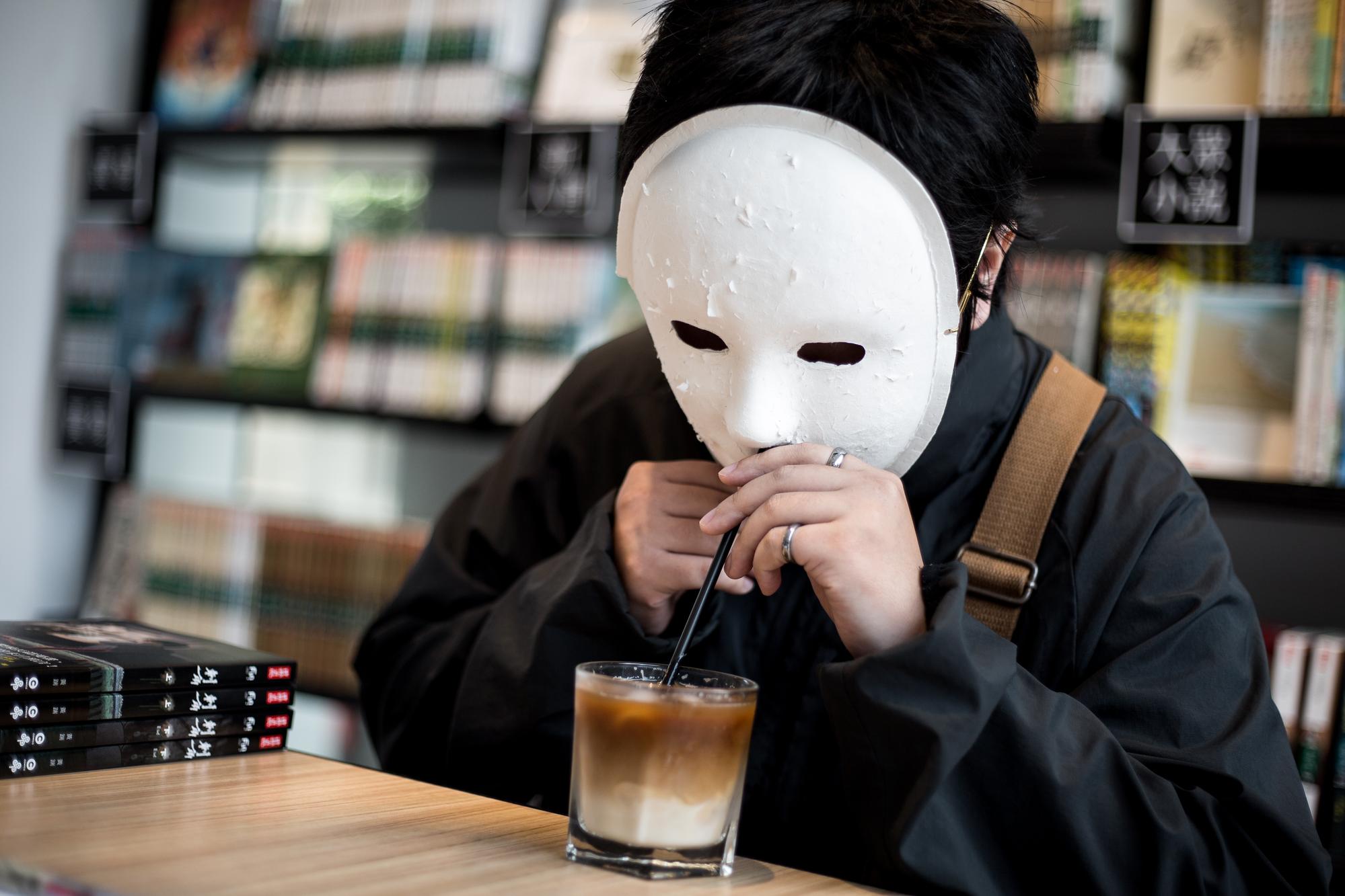 採訪到一半，黃踹忽然拿出自備的吸管，嘴巴就著面具的鼻孔處啜飲咖啡，畫面有些滑稽。