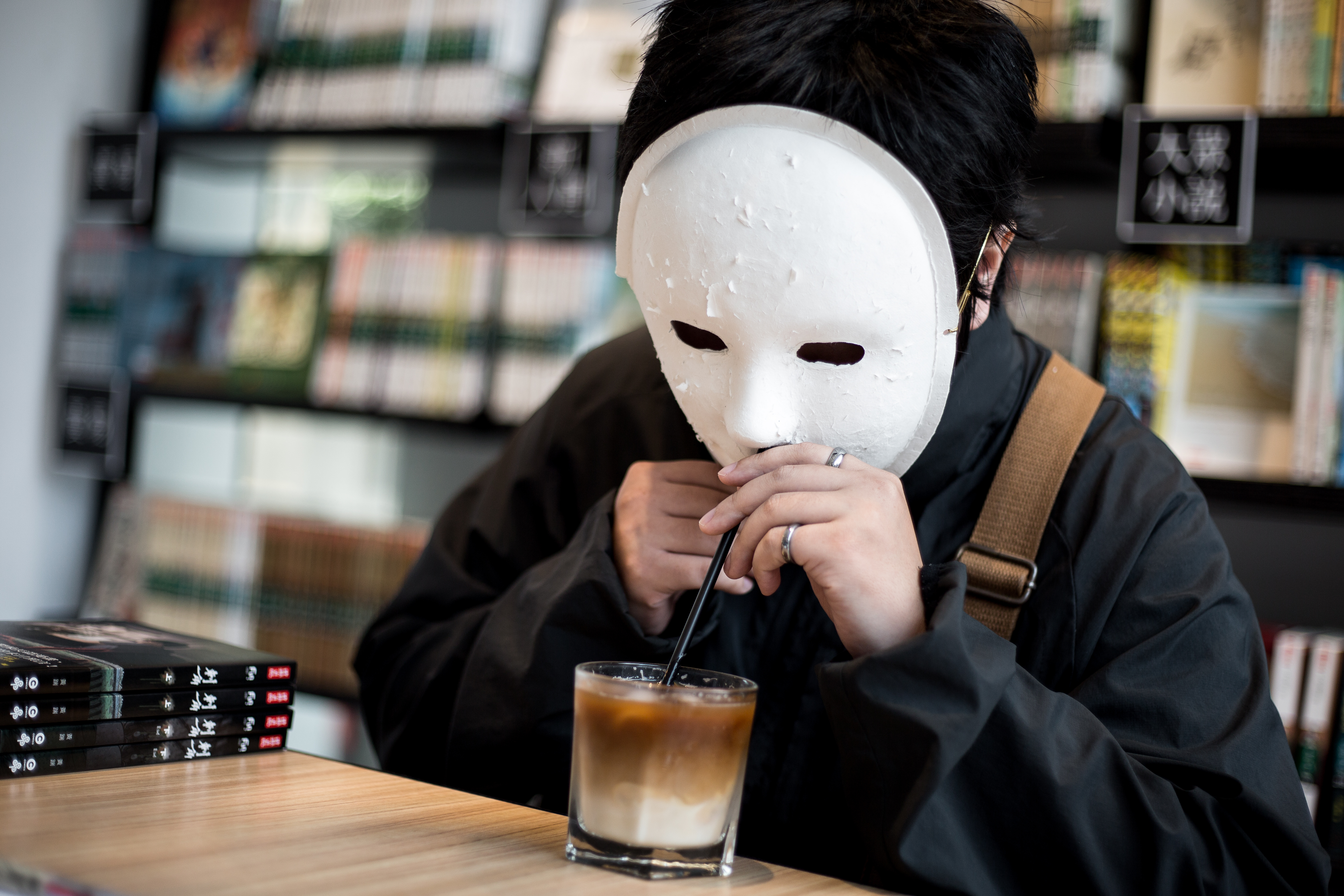 採訪到一半，黃踹忽然拿出自備的吸管，嘴巴就著面具的鼻孔處啜飲咖啡，畫面有些滑稽。