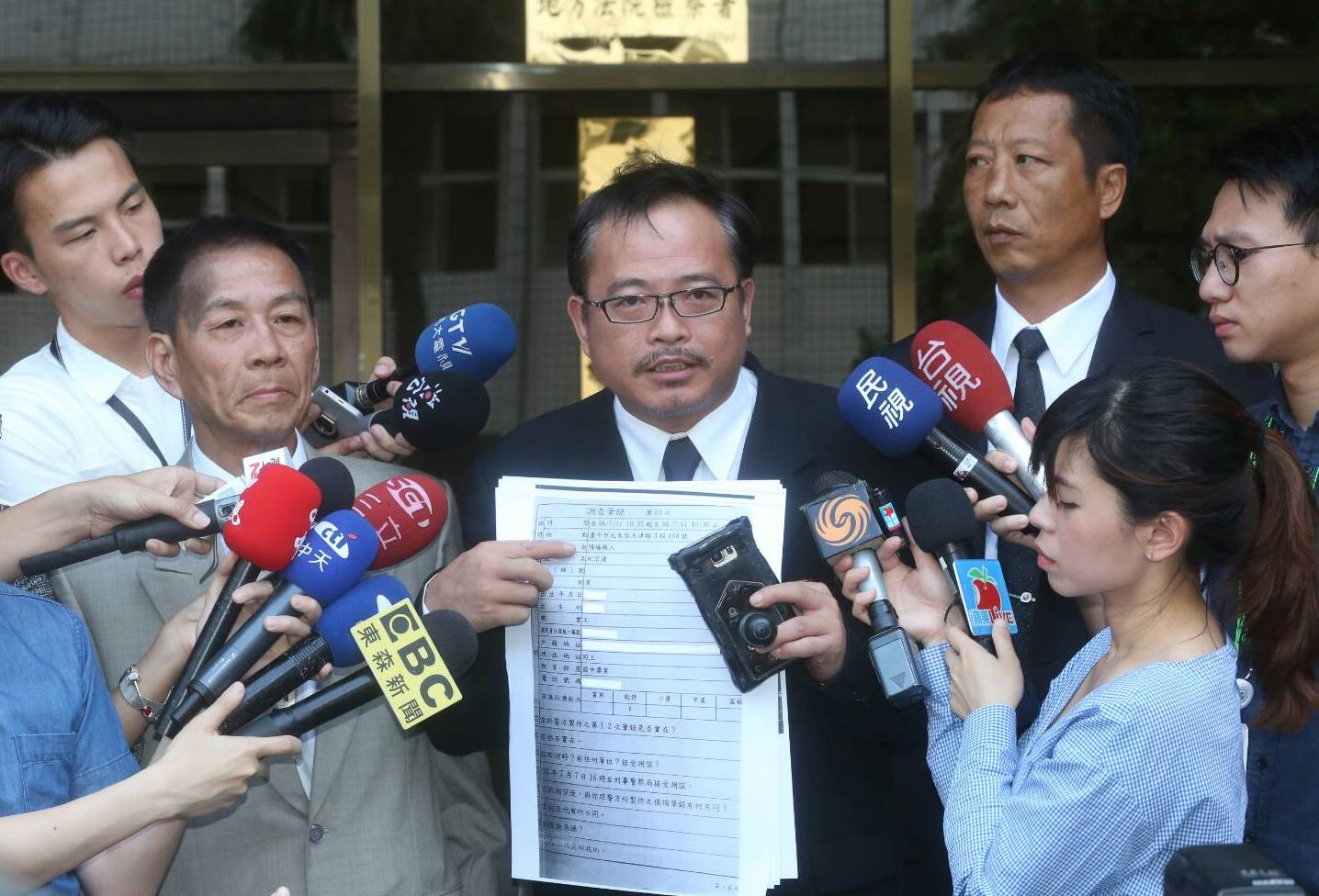 參與教唆買凶槍擊蔡正元服務處的翁炳堯今天上午在律師周武榮（圖中）陪同下，到台北地檢署聲稱要供出當年買凶的幕後藏鏡人。