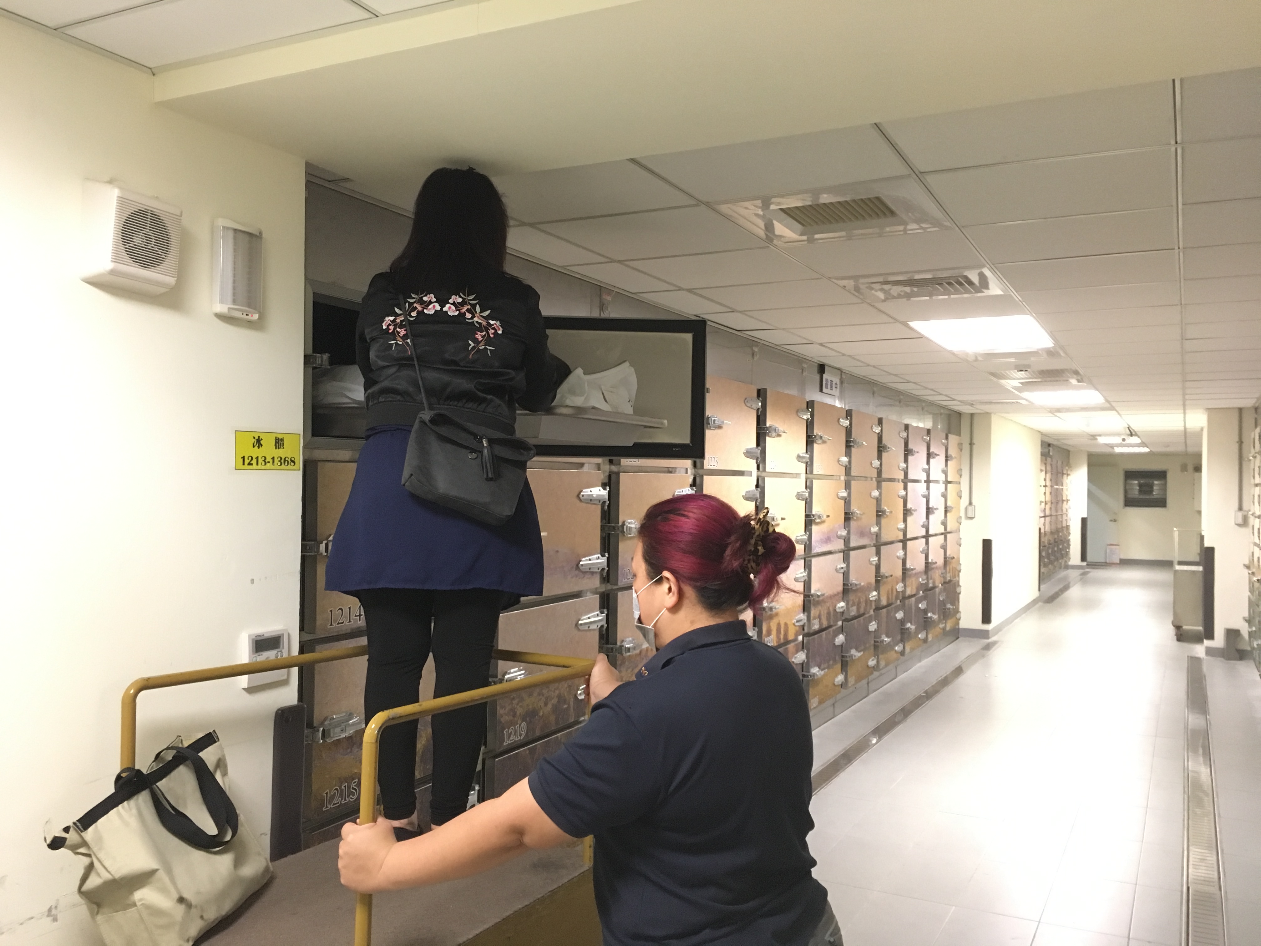 投訴人羅女在冰櫃前輕撫丈夫已經發黑的屍體泣不成聲，怒控北市殯葬處惡法忽視人性。（讀者提供）