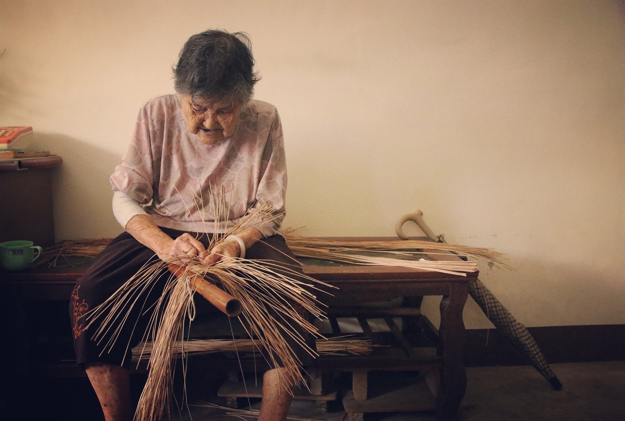 94歲高齡的許陳真阿嬤，至今仍專注地以苑裡藺草編織名片夾。（圖片提供／藺子，攝影／李易紳）