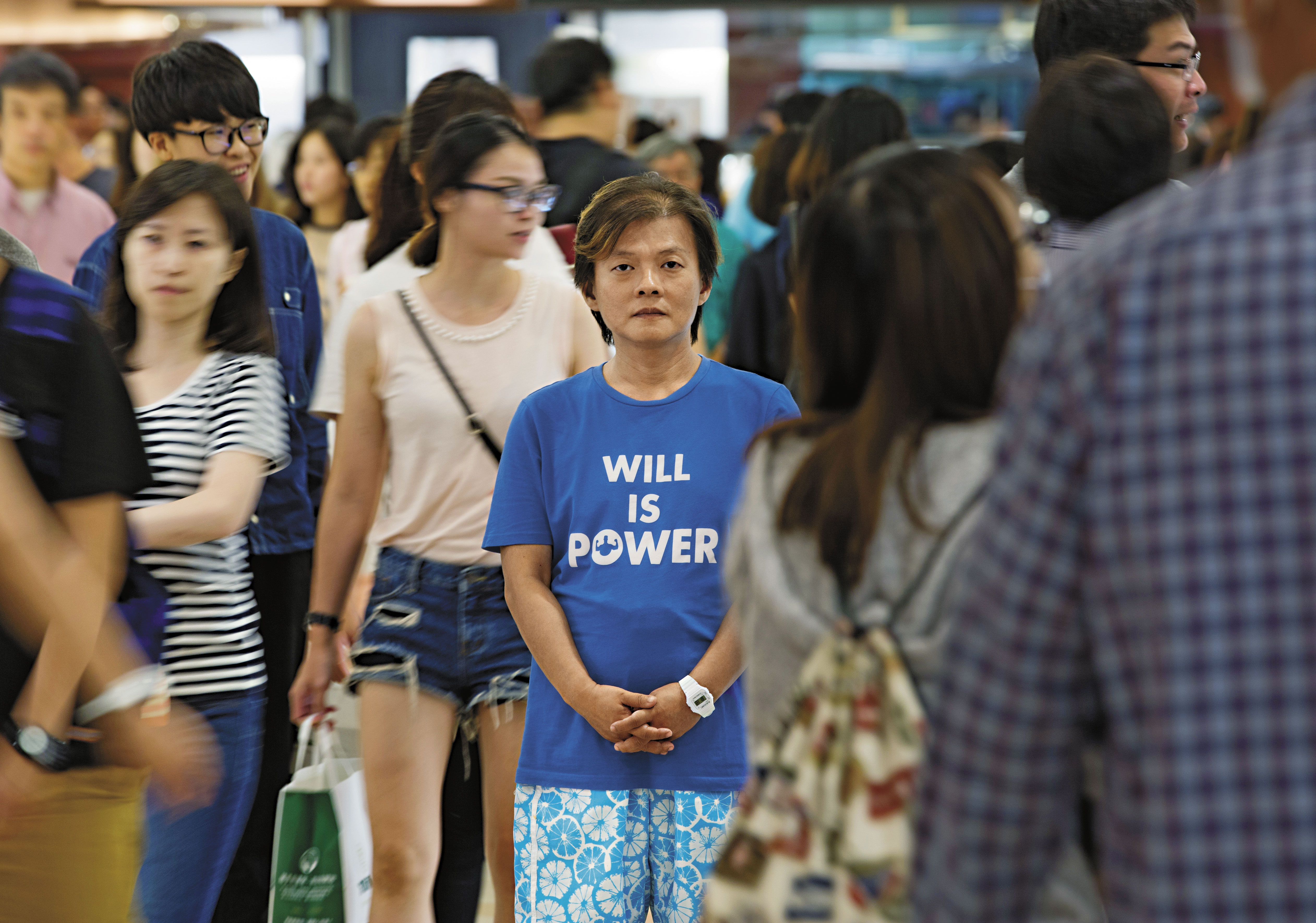 站在人群中，丘愛芝顯得更嬌小，他的生命故事深沉，但堅強的意志給了他面對自我的力量，如同T恤上的標語。